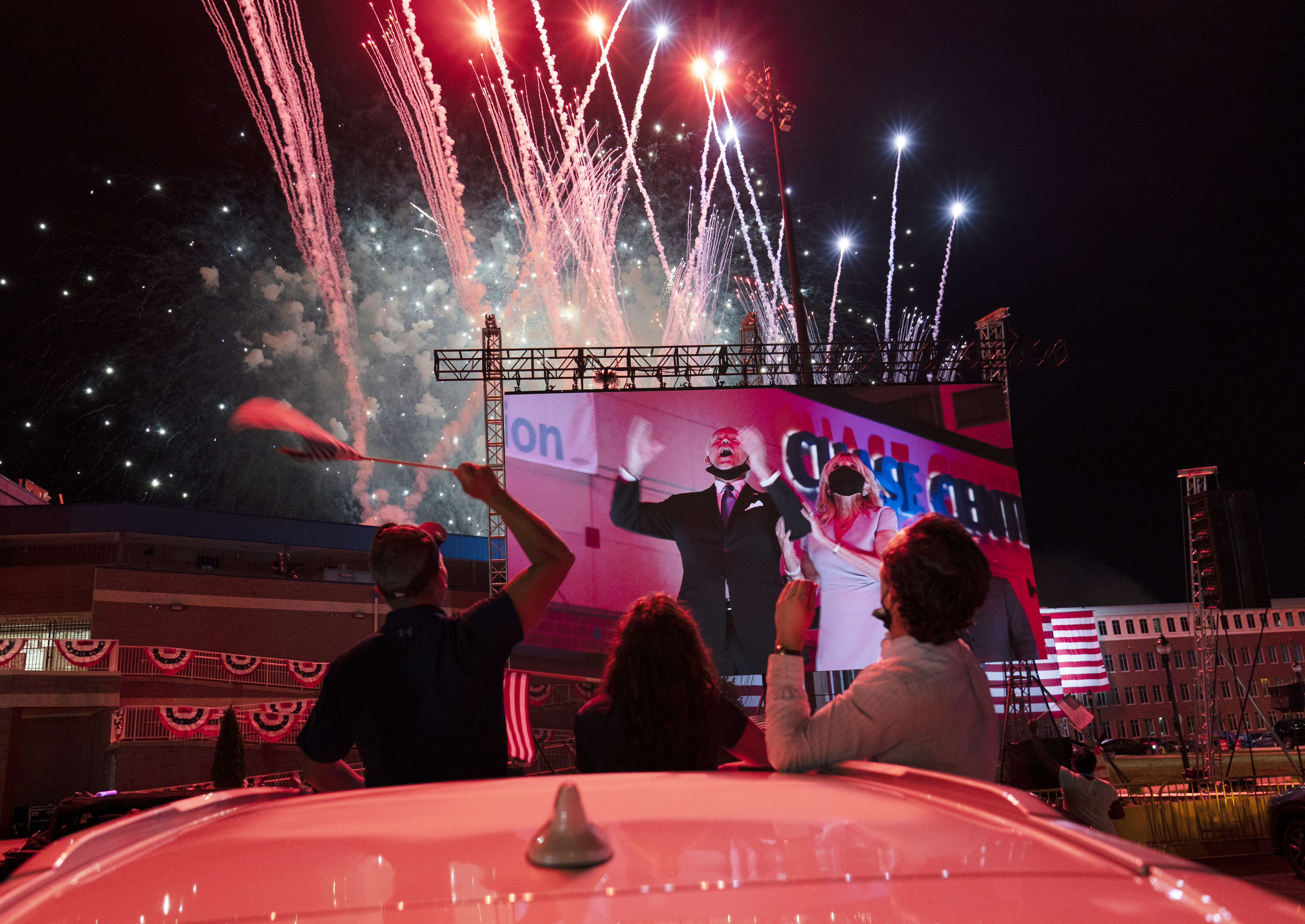 Supportes cheered from their cars as Democratic presidential candidate former Vice President Joe Biden and his wife Jill Biden are seen on a monitor as fireworks went off.