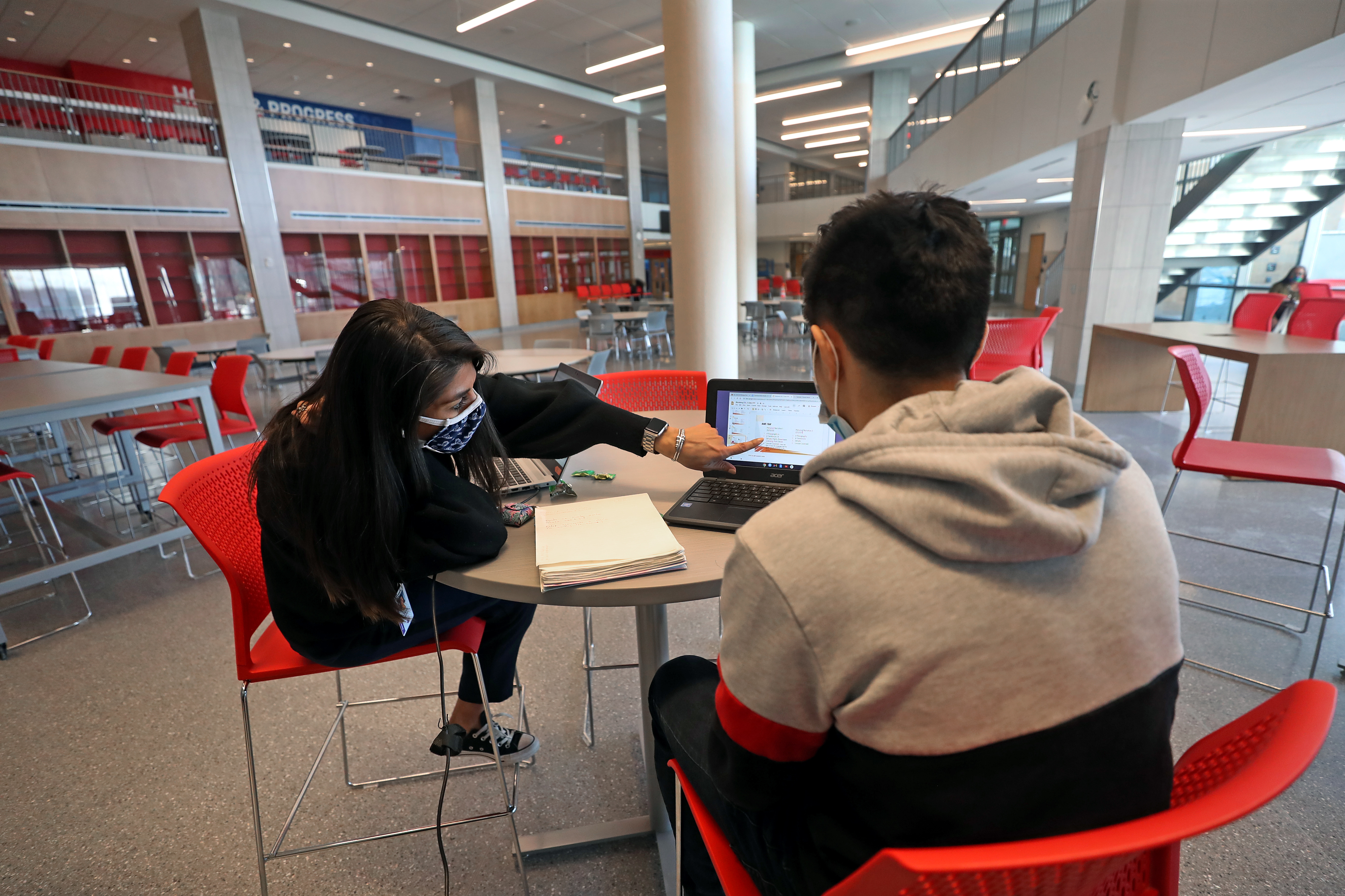 Dean of Students Catarina Saenz works with a student in the cafeteria at Somerville's new high school.