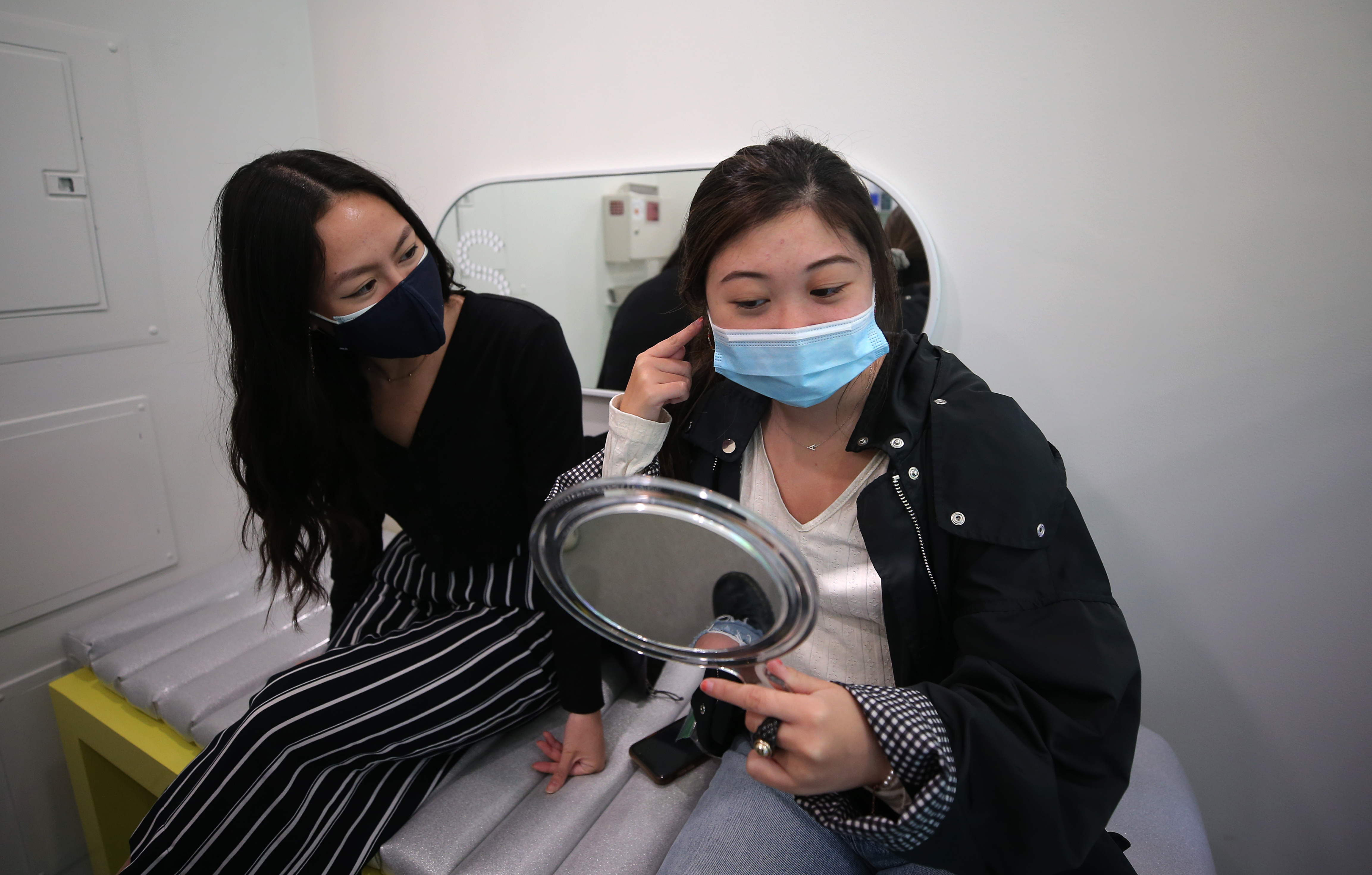 Tiffany Tsang looks at the ear of Allison Lam. They are both Boston University students who visited Studs this week.