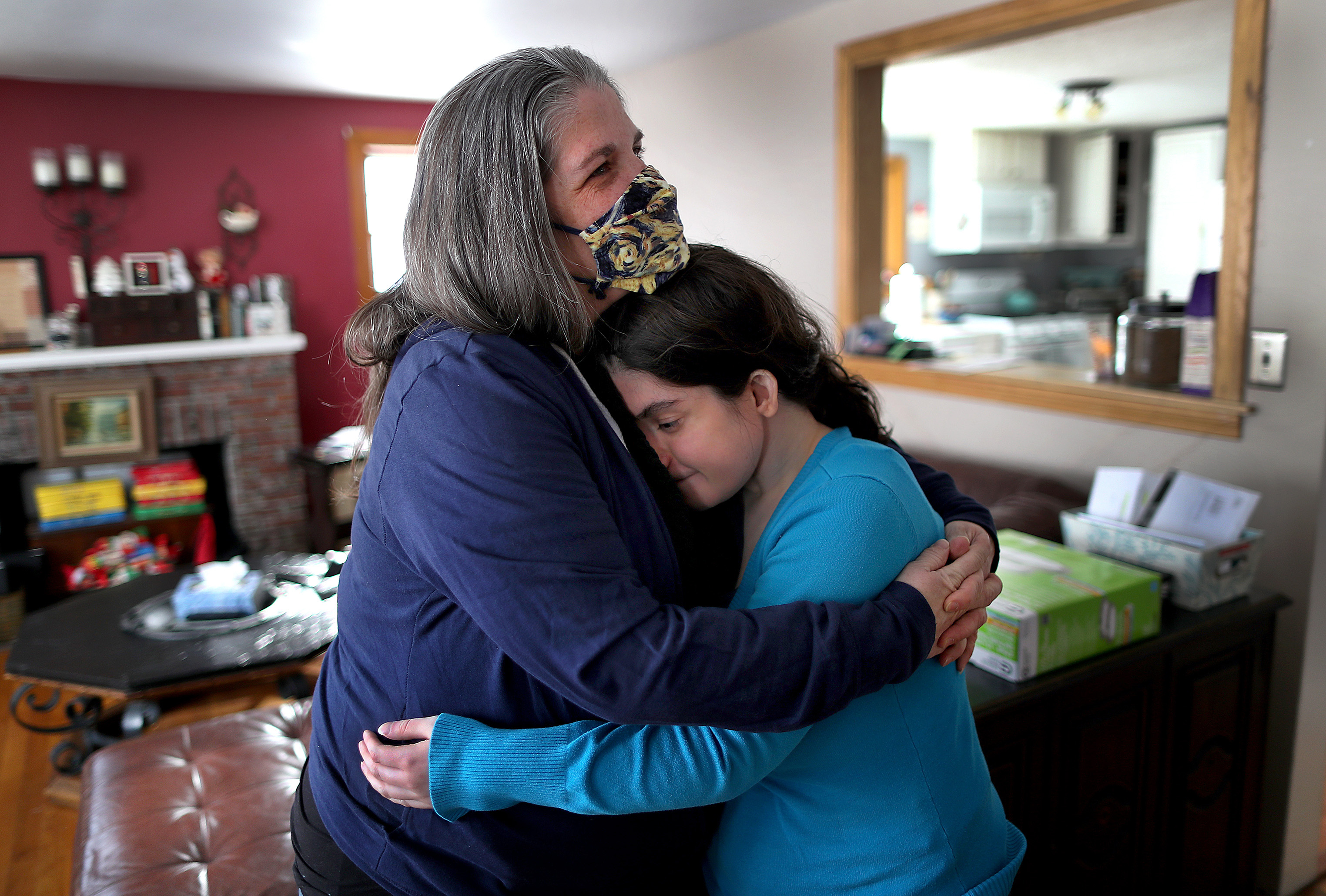 Lisa Jennings (left) hugged her daughter Monica in their Weymouth living room. Monica Jennings has a chromosome disorder called 22q11.2 deletion syndrome and several other medical issues. But under the state's rules, she does not qualify for an early COVID-19 vaccine under the Massachusetts distribution plan.