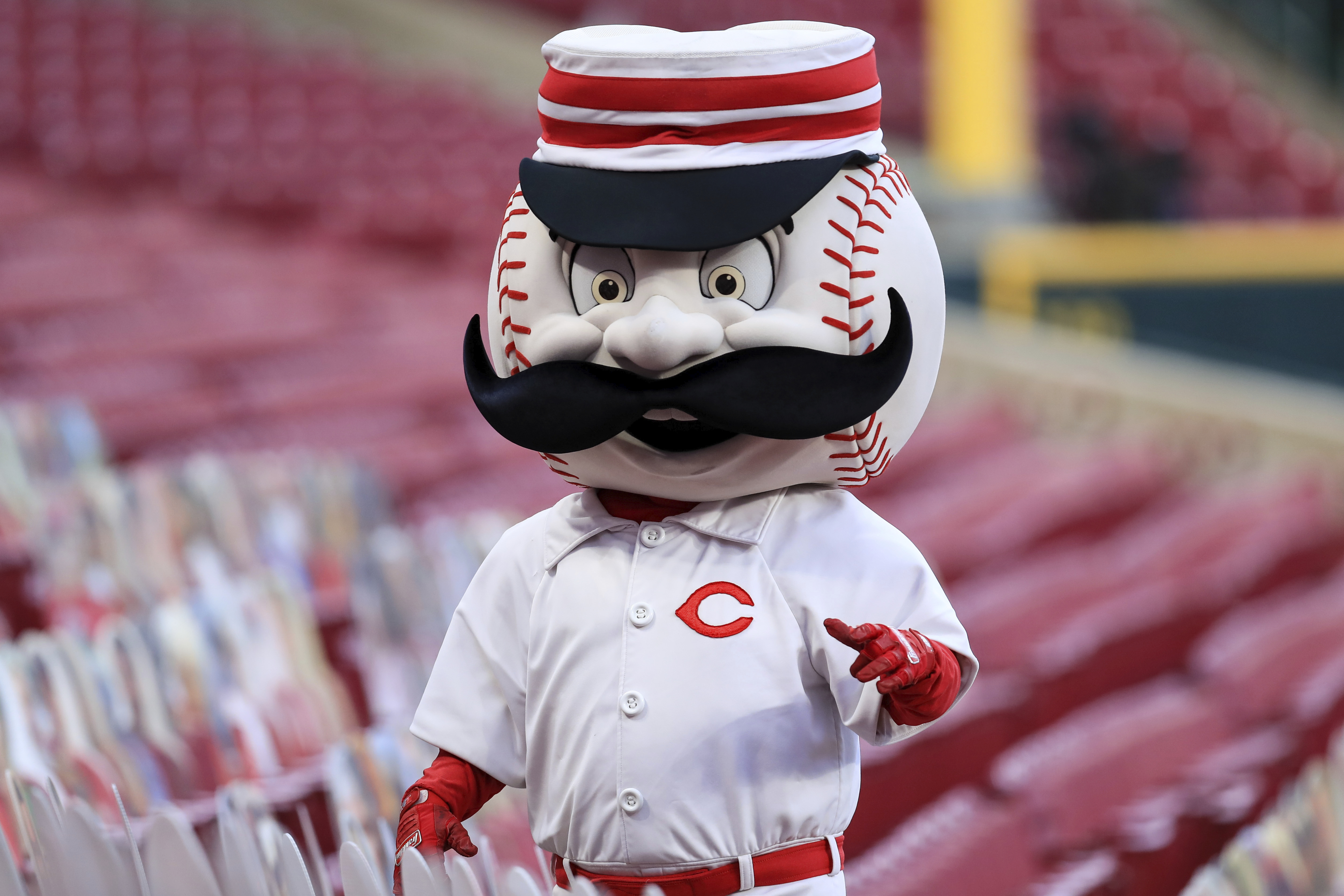 The Cincinnati Reds mascot Mr. Redlegs sits in the dugout during