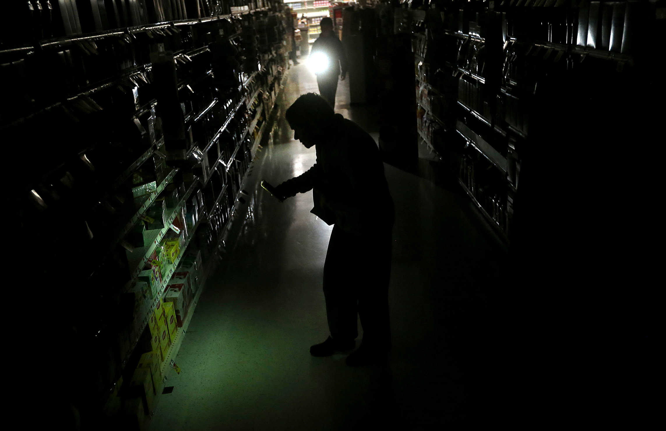 Candace Lofgren shoped inside an open but dark Stop & Shop in Falmouth. Patrons were using the flashlights on their cellphones to navigate the trip.