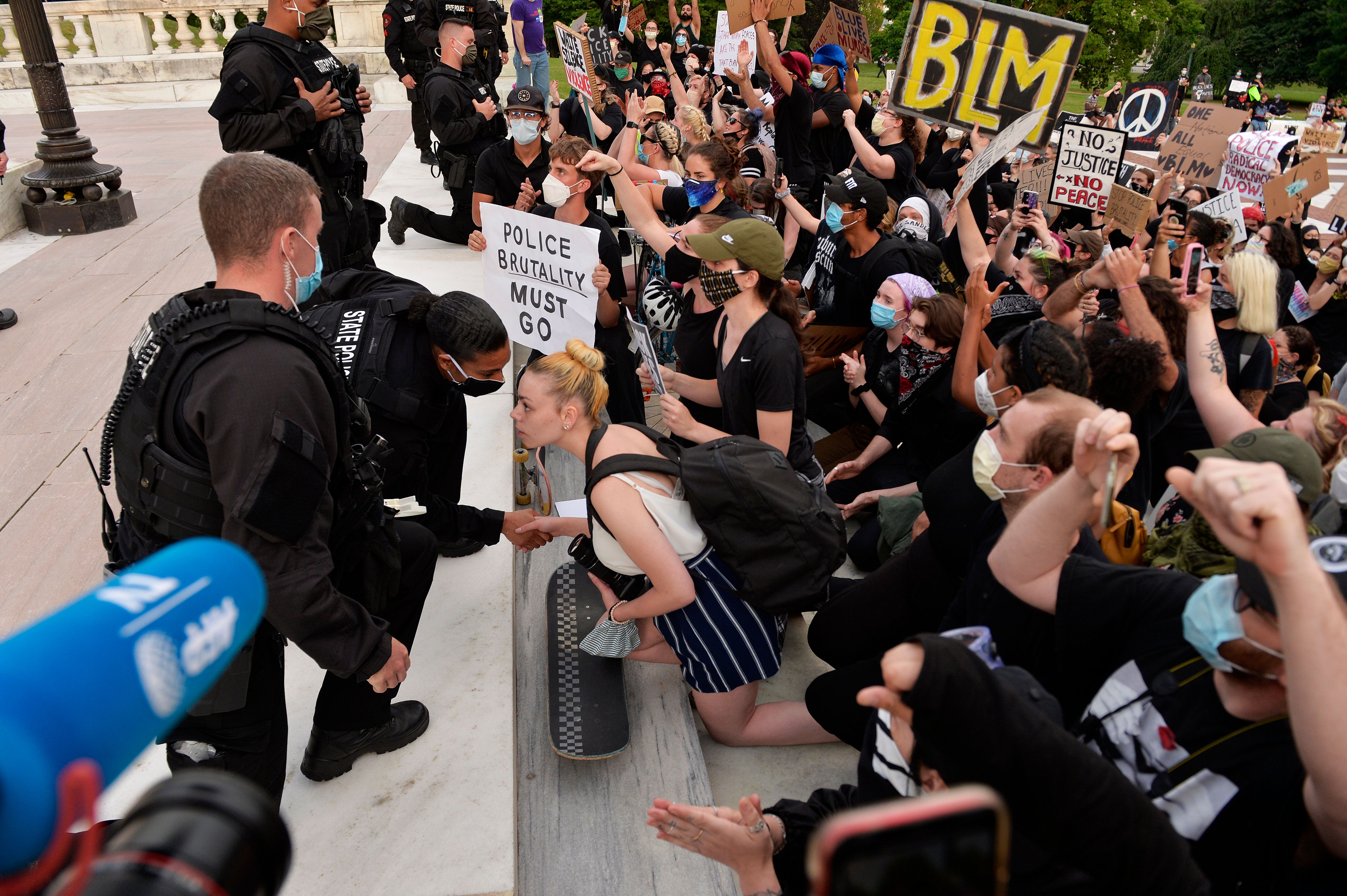 Police officers kneel down and shake hands with protesters during a Black Lives Matter rally in Providence, Rhode Island on June 5, 2020.