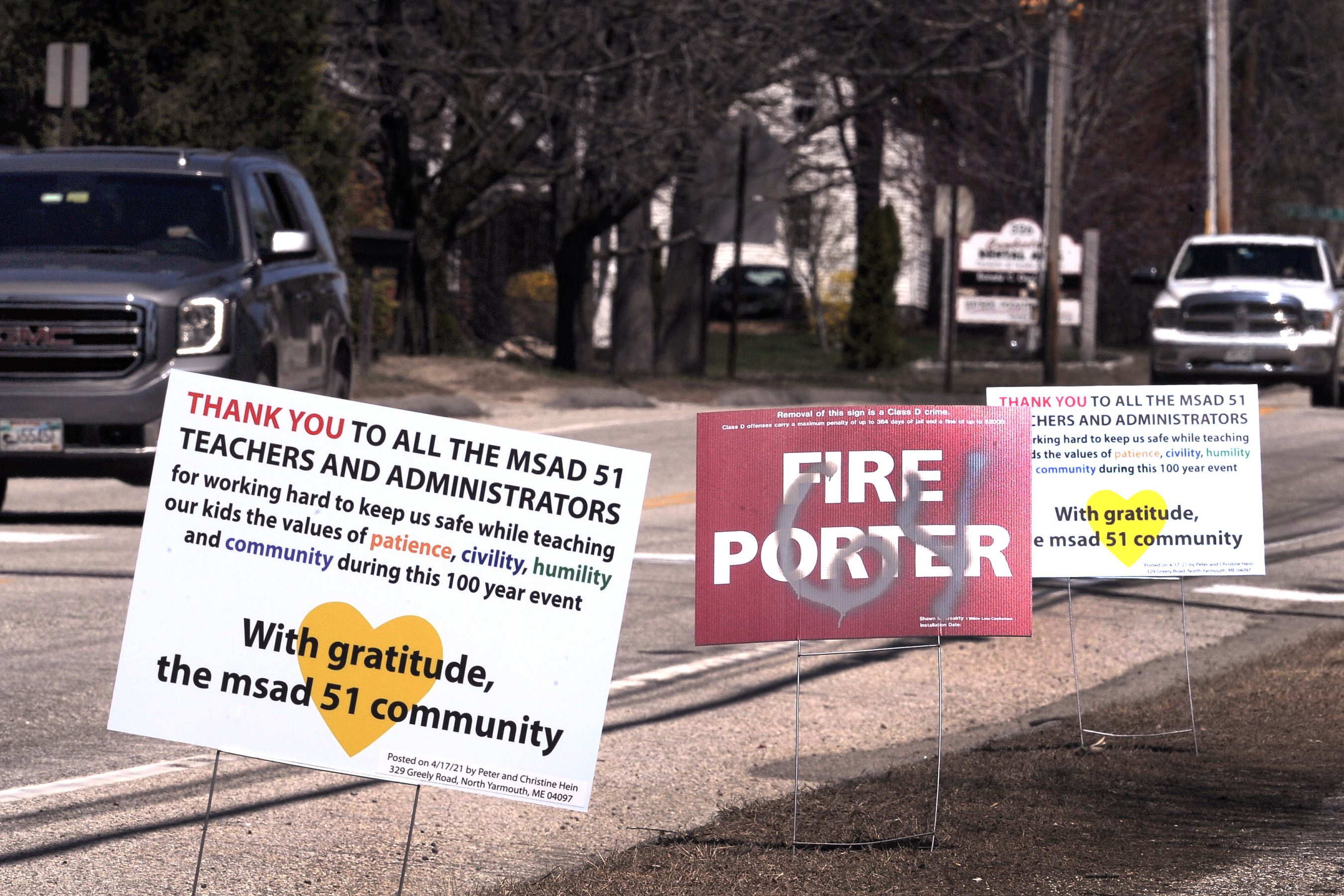 A sign on Main Street in Cumberland, Maine, advocates firing Cumberland-North Yarmouth school district Superintendent Jeff Porter, as bordering signs urge positivity.