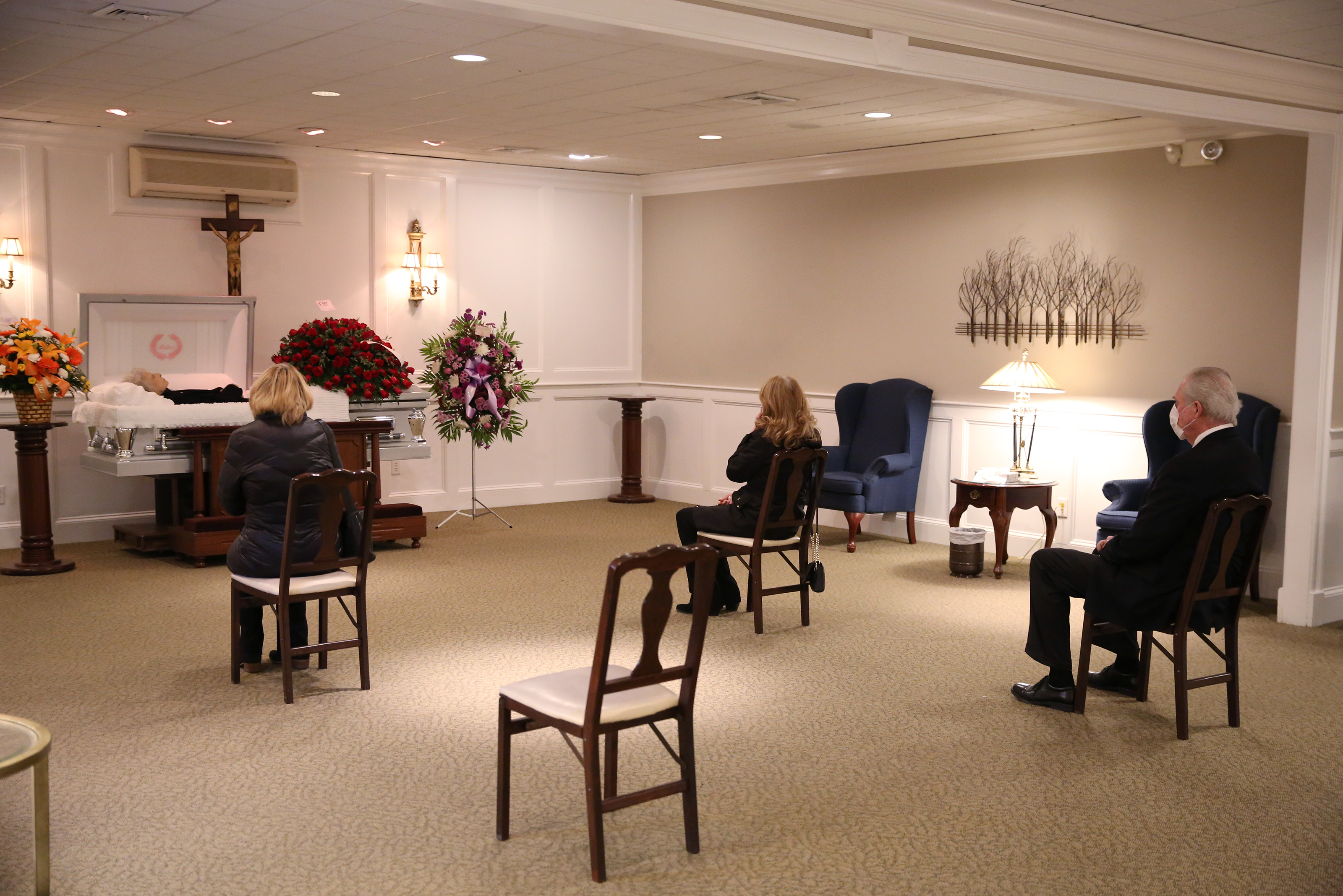 Family members of Annette Nazzaro maintain a social distance during her wake at the Ruggiero Family Memorial Home in East Boston. Nazzaro lived to be 100 before succumbing to coronavirus.