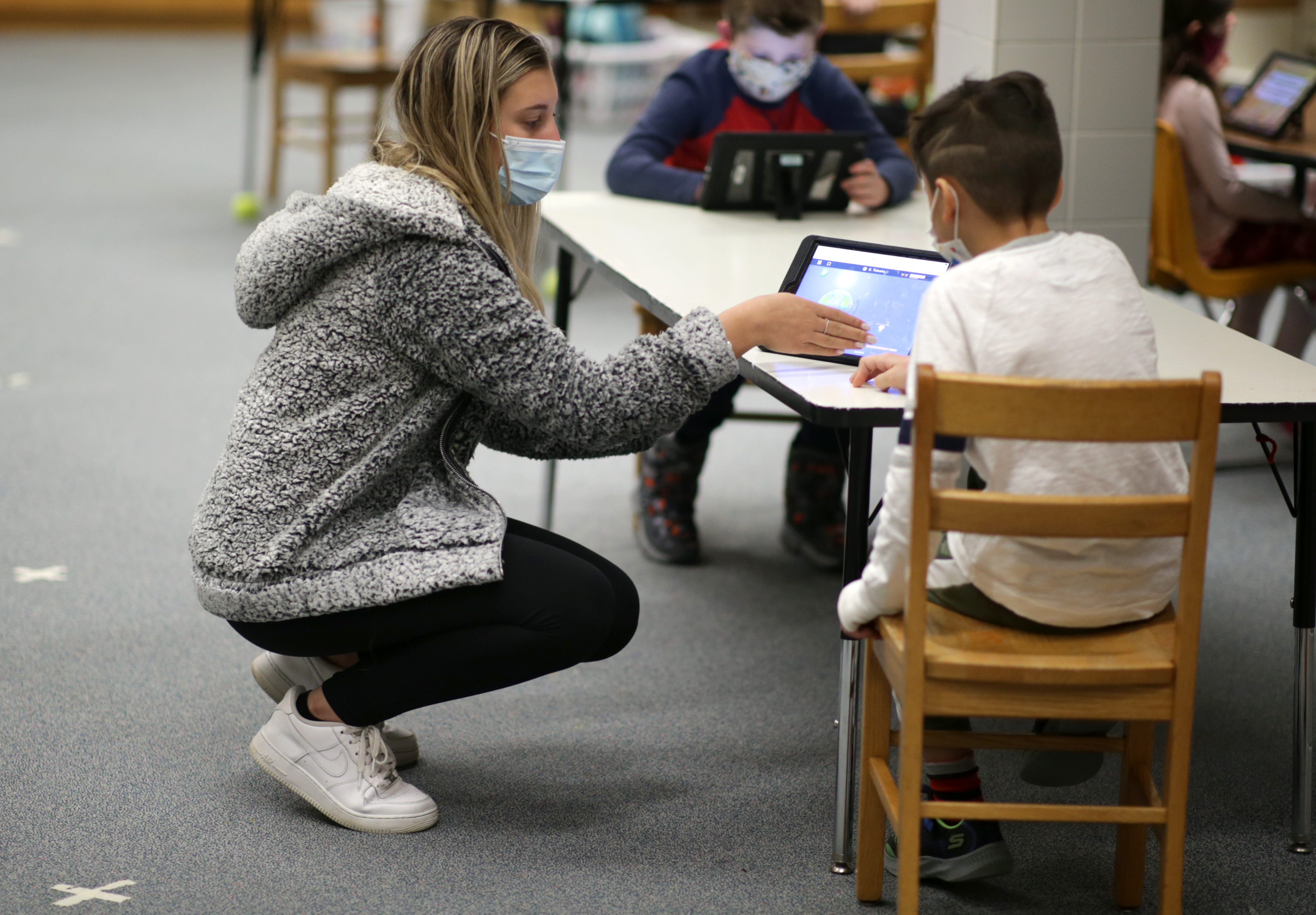 Staff member Tori Smith works with Enzo Teixeira, 7, at the YMCA of the North Shore's in-person program at the Ayers Ryal Side School in Beverly.