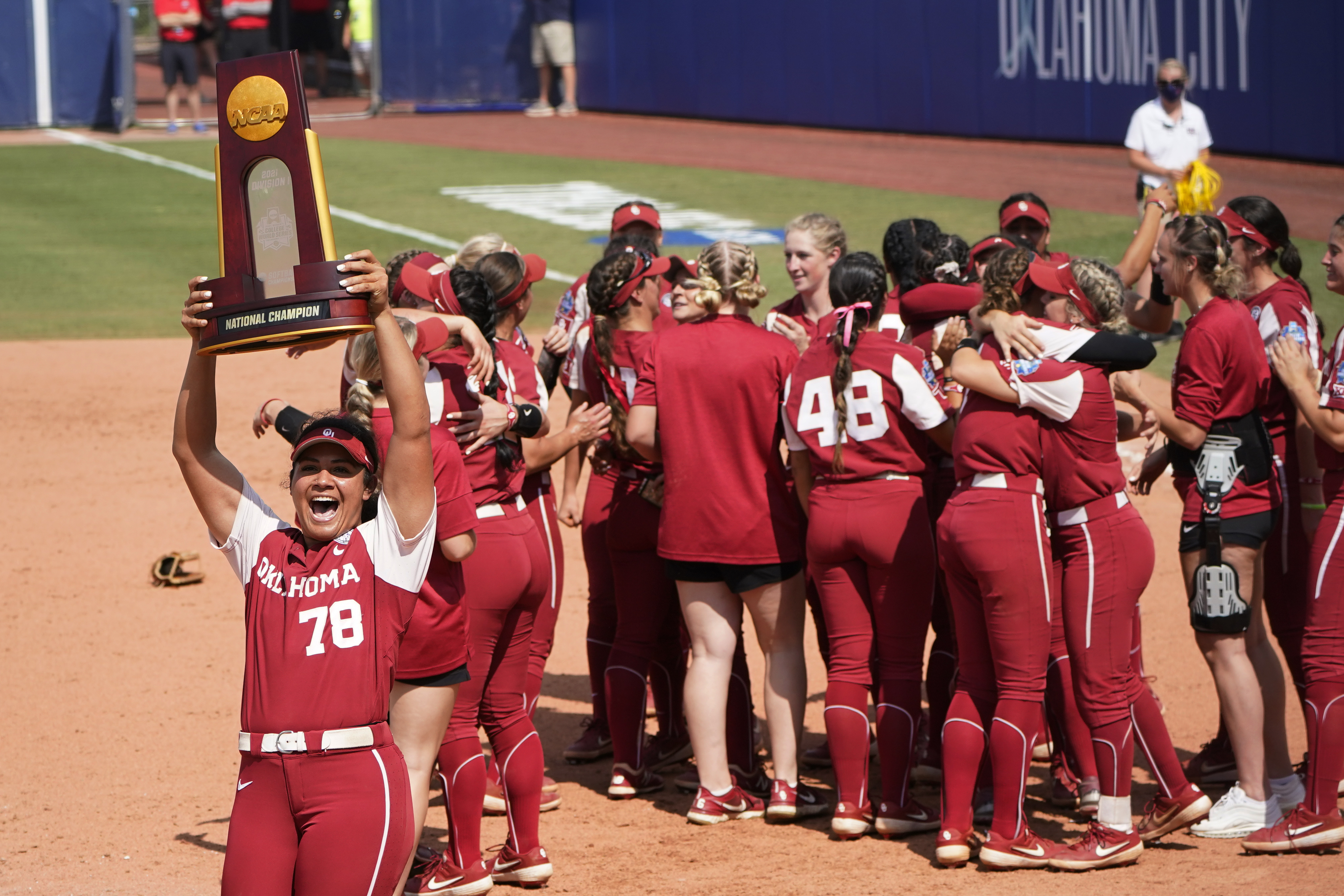 Jocelyn Alo, who hit four homers in the World Series, carries the trophy toward Oklahoma fans as the postgame celebration continues.