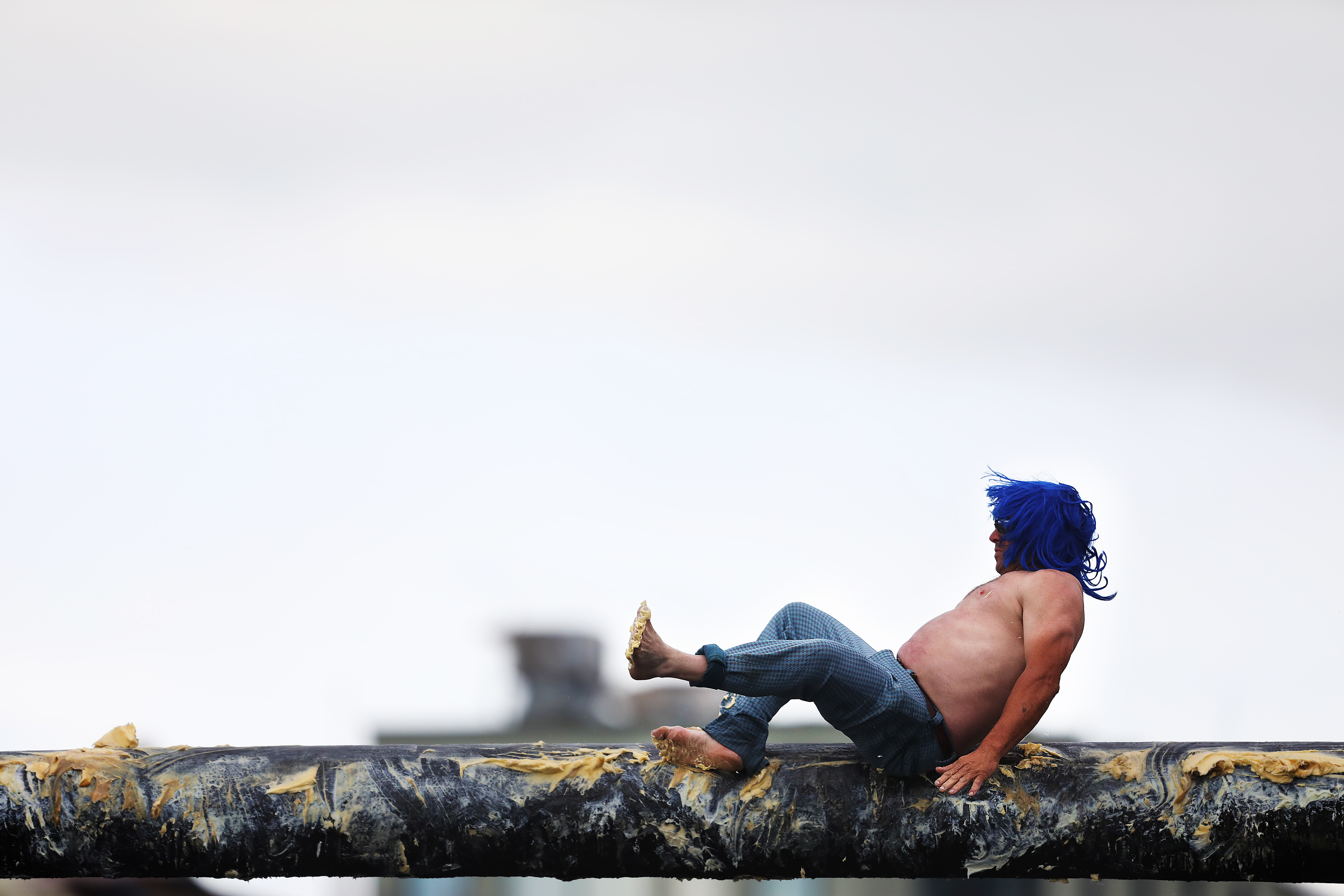 A competitor fell during the Greasy Pole Walk of Champions at Pavilion Beach in Gloucester on June 30.