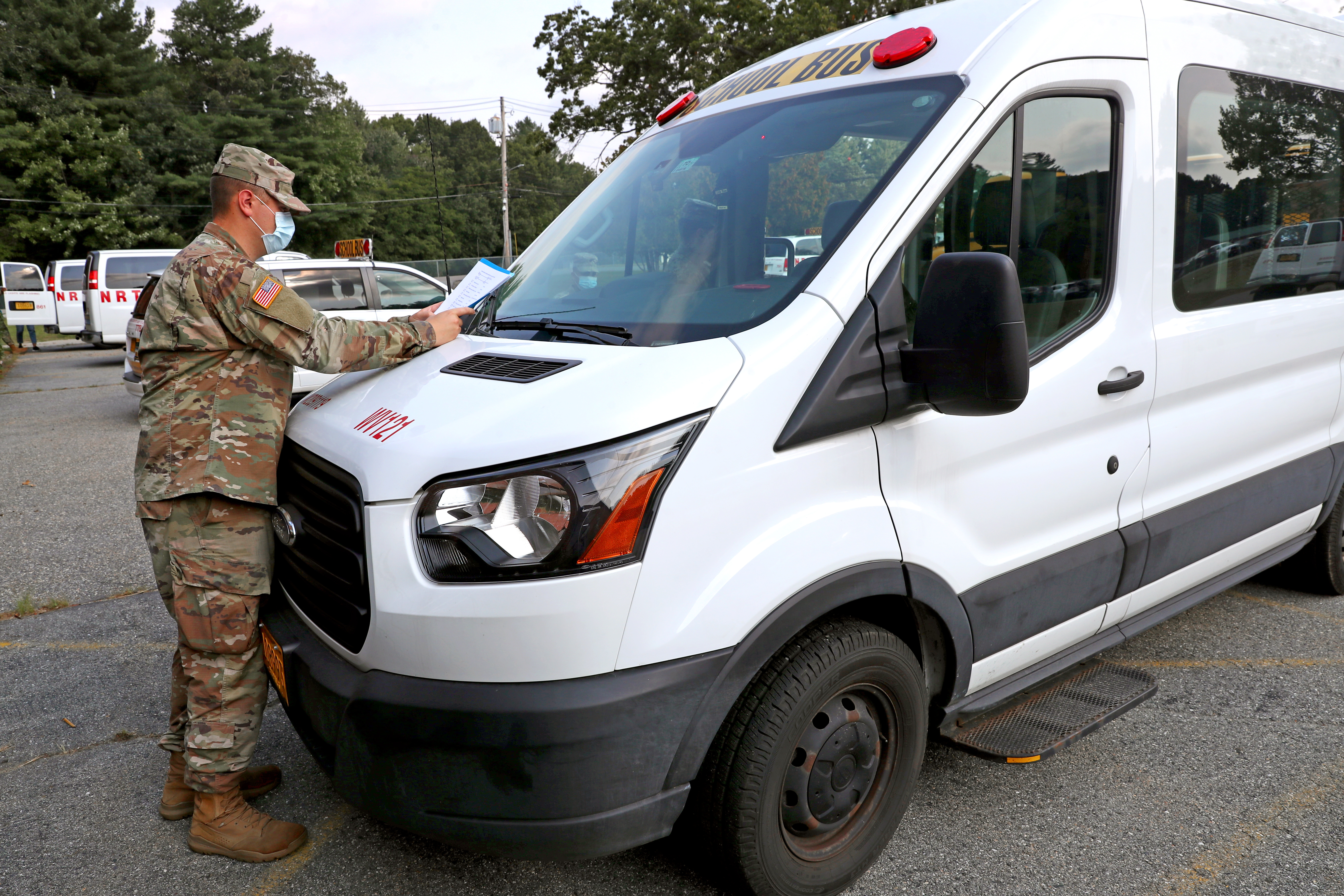 National Guard MP Corporal Nick Diaz goes over some instructions on the hood of a school bus.
