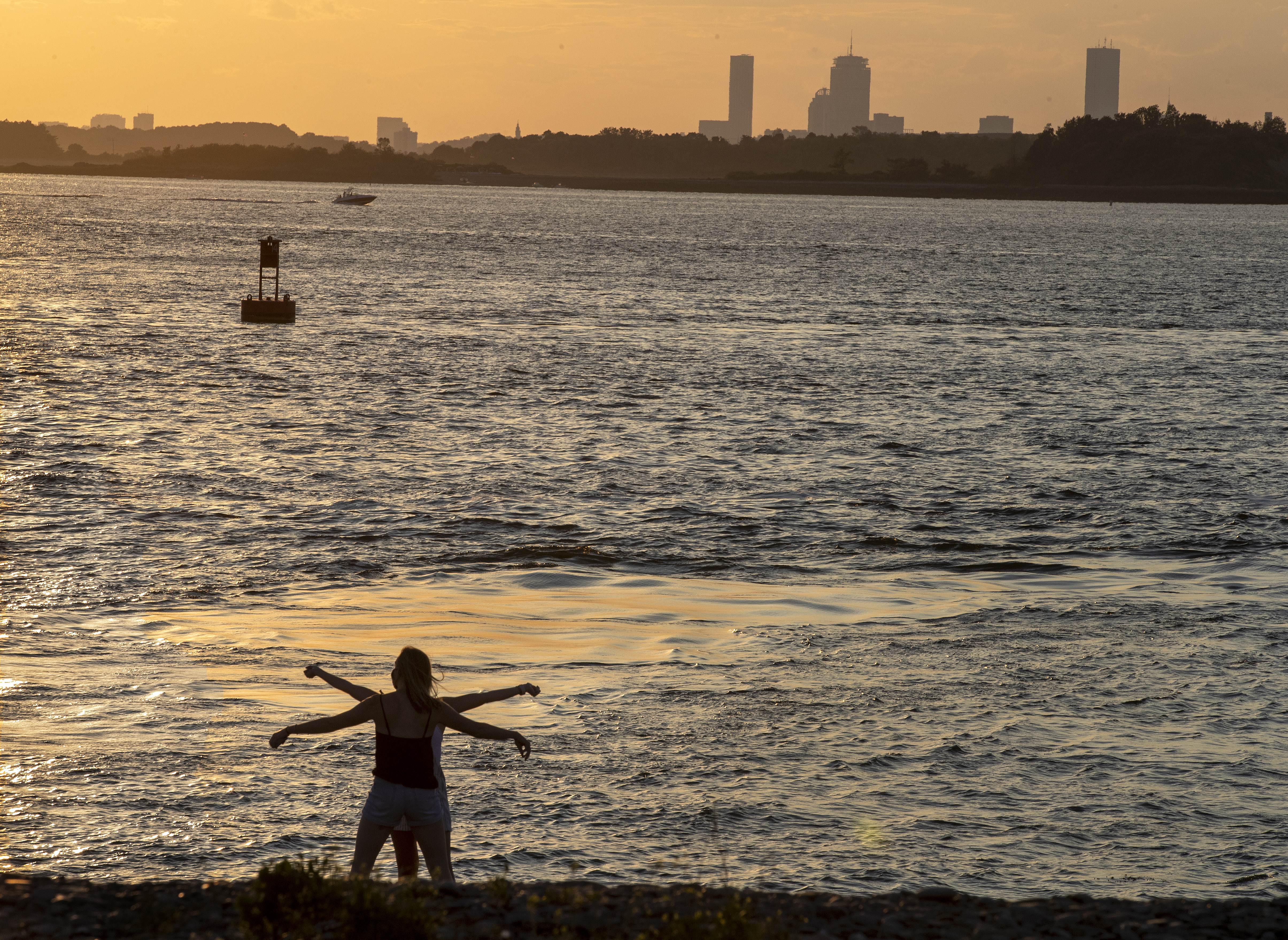 A couple danced before the setting sun in Hull with the Boston skyline spread out in the distance.