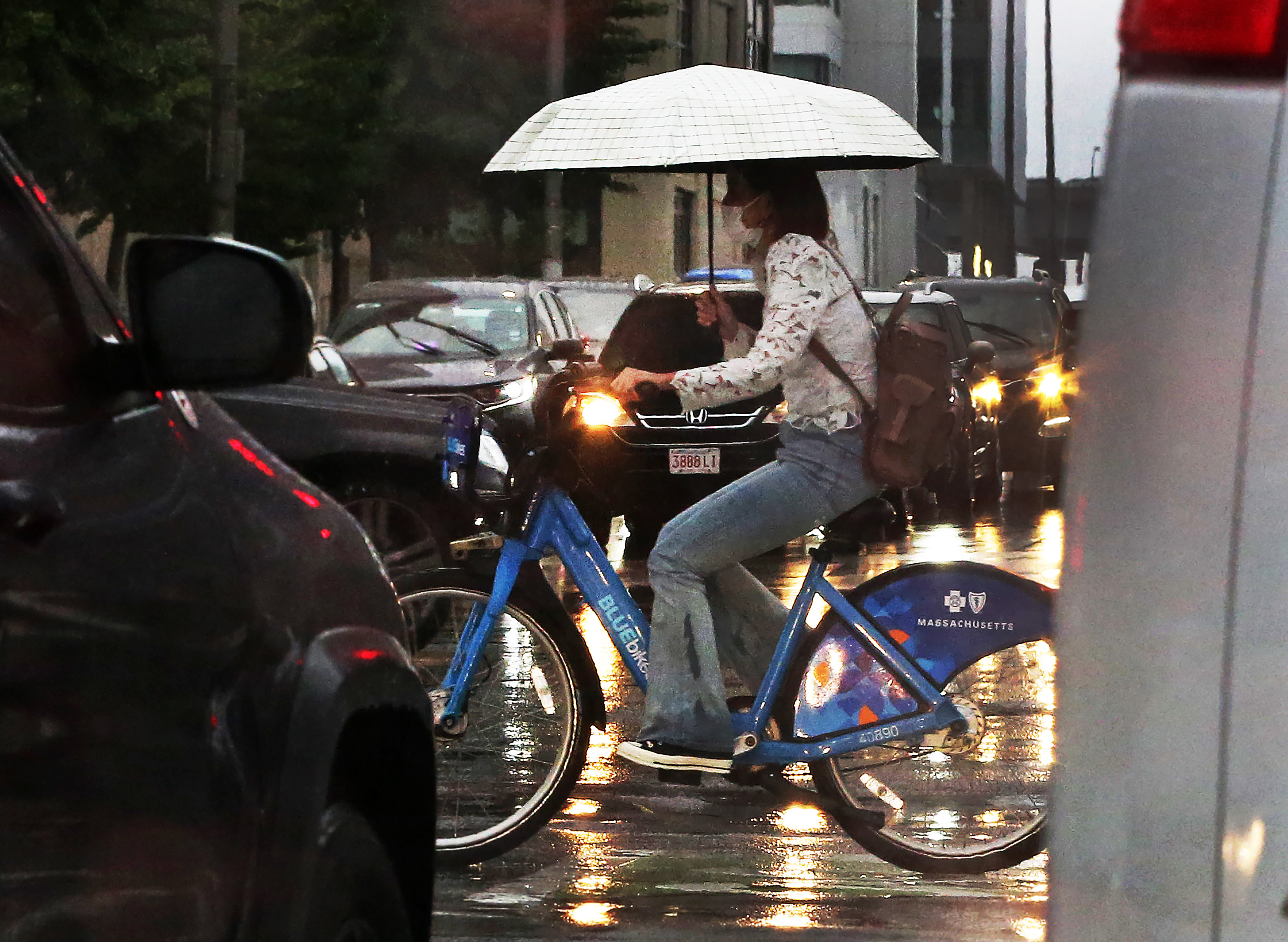 As the remnants of Hurricane Ida move into New England, an umbrella toting bicycle rider crosses the street at the intersection of the Monsignor O'Brien Highway and Land Boulevard in Cambridge on Thursday.