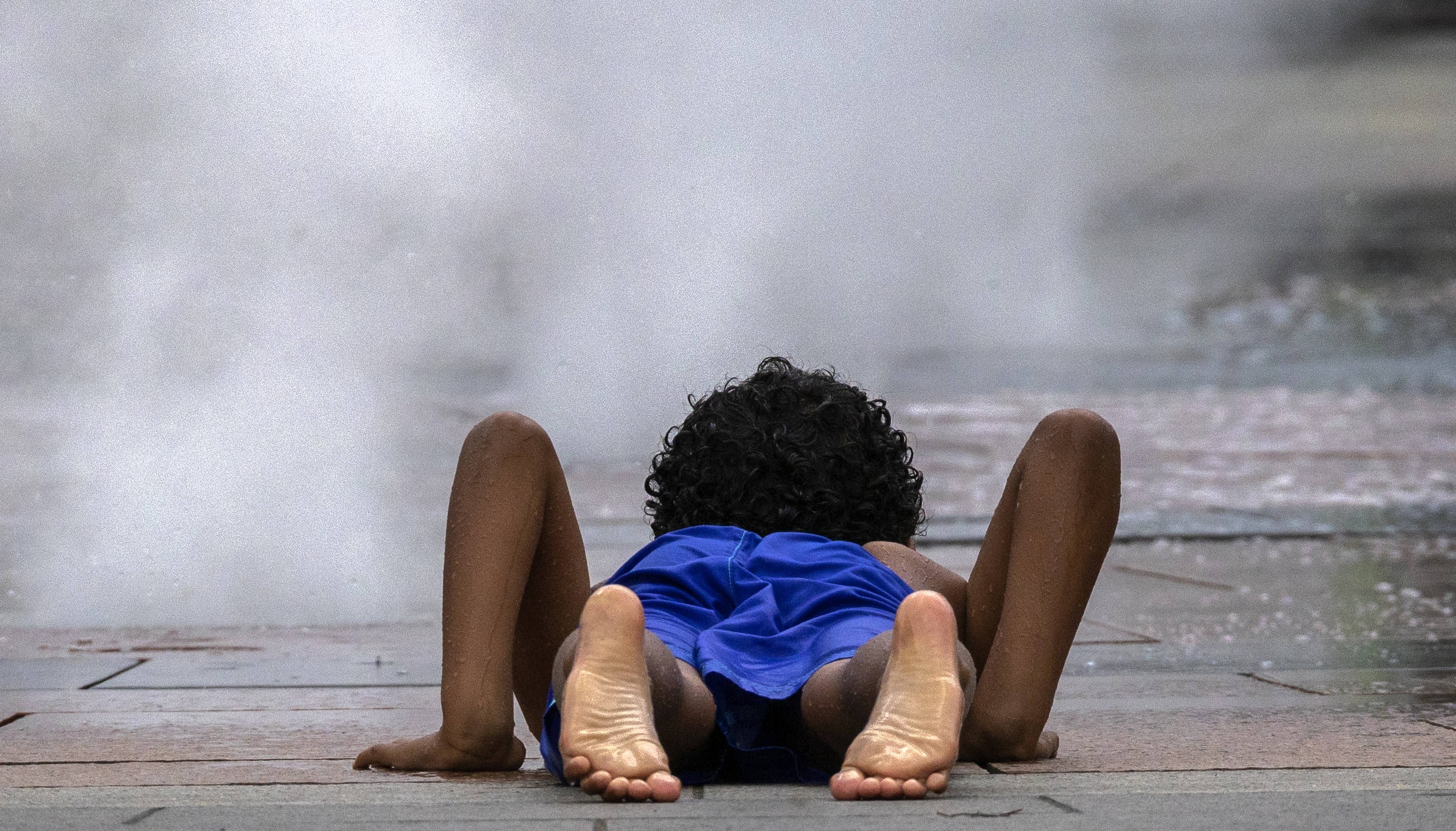 A boy watched the mist raised from a fountain on the Rose Kennedy Greenway in Boston.