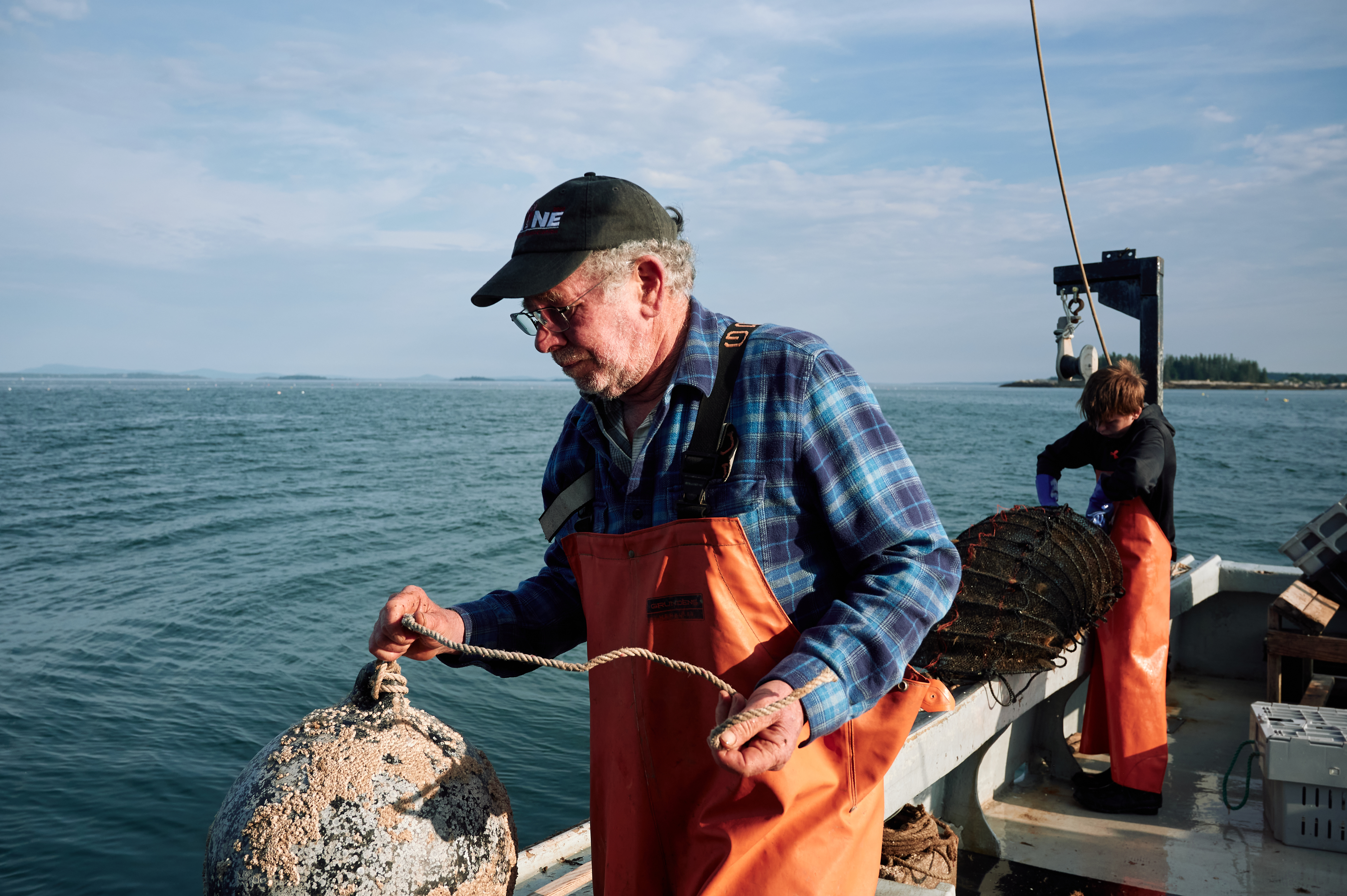 Marsden Brewer switched from fishing to running a scallop farm. He’s pictured on the bay with his grandson.