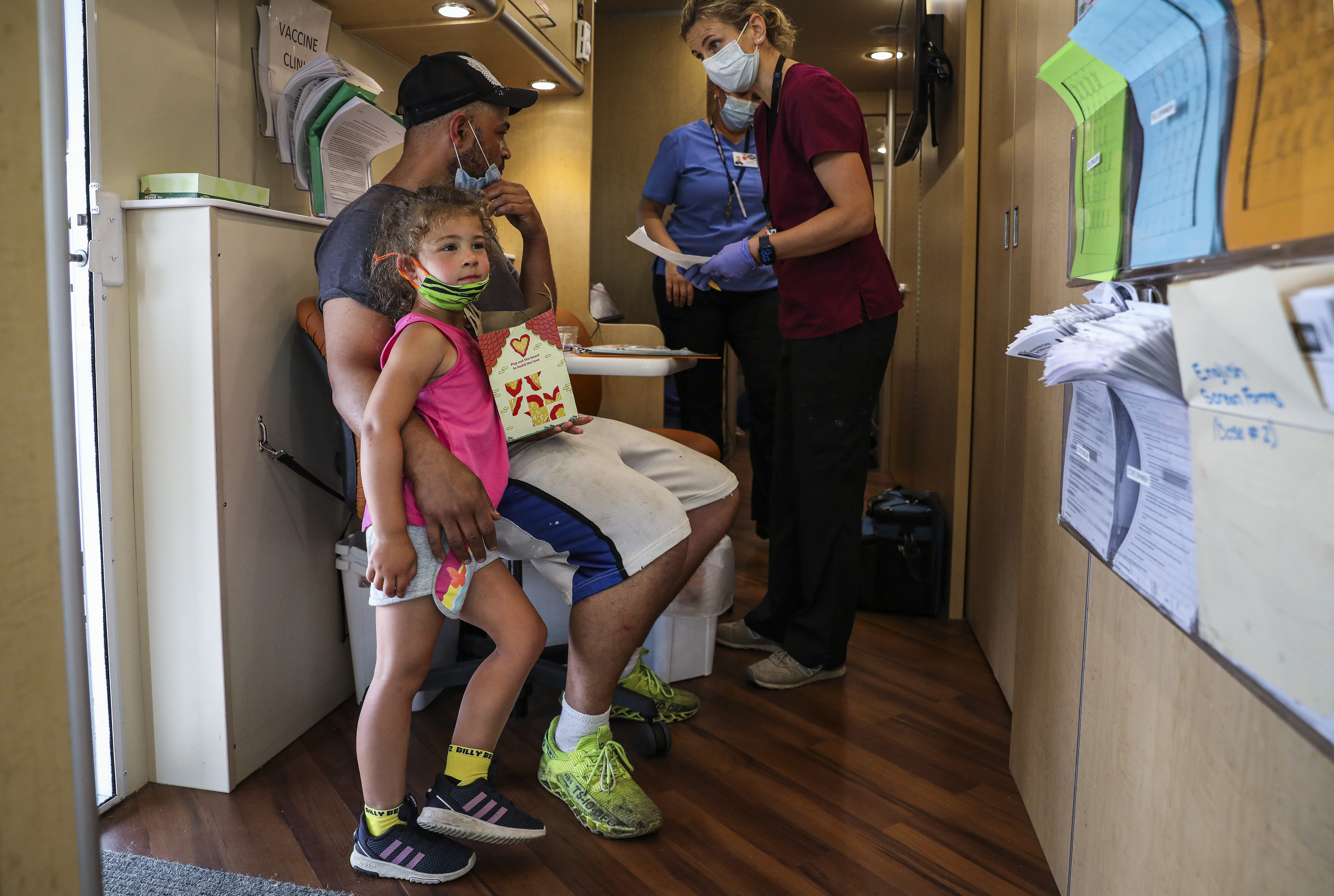 Phillip Griffin rested his arm around his 4-year-old daughter, Harper, while he received the COVID-19 vaccine from Kornelia Krzyzanowska while on board the Community Health Programs' Mobile Health Unit. If the mobile health unit had not visited Monroe Muffler, where Griffin works, he says he would have not had the time to to receive vaccine elsewhere.
