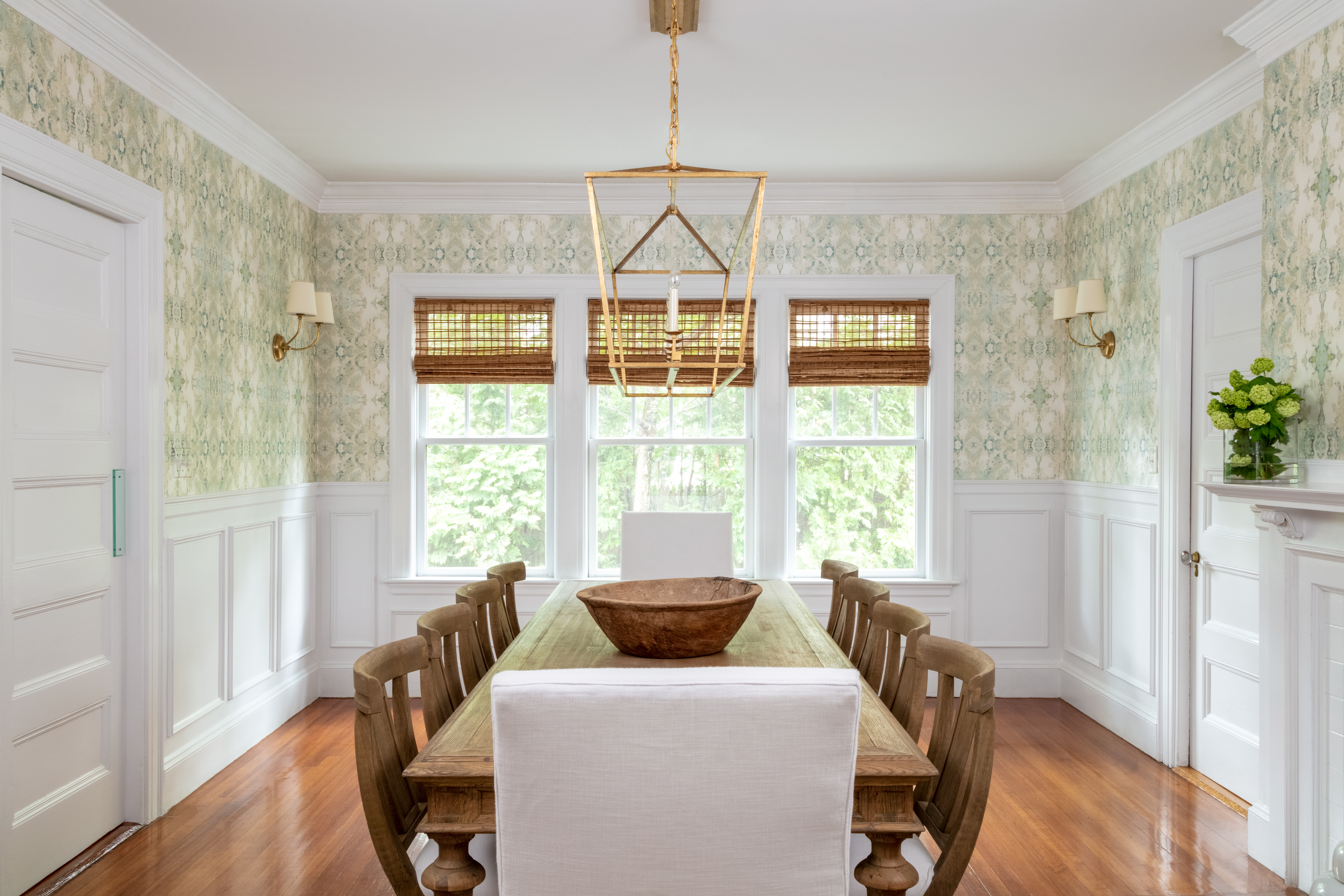 Candice Olson wallpaper infuses a fresh feel in the dining room, where fixtures from Circa Lighting tie to the brass hardware in the kitchen. McGuill chose textural natural shades over drapery, which would have weighed down the space.