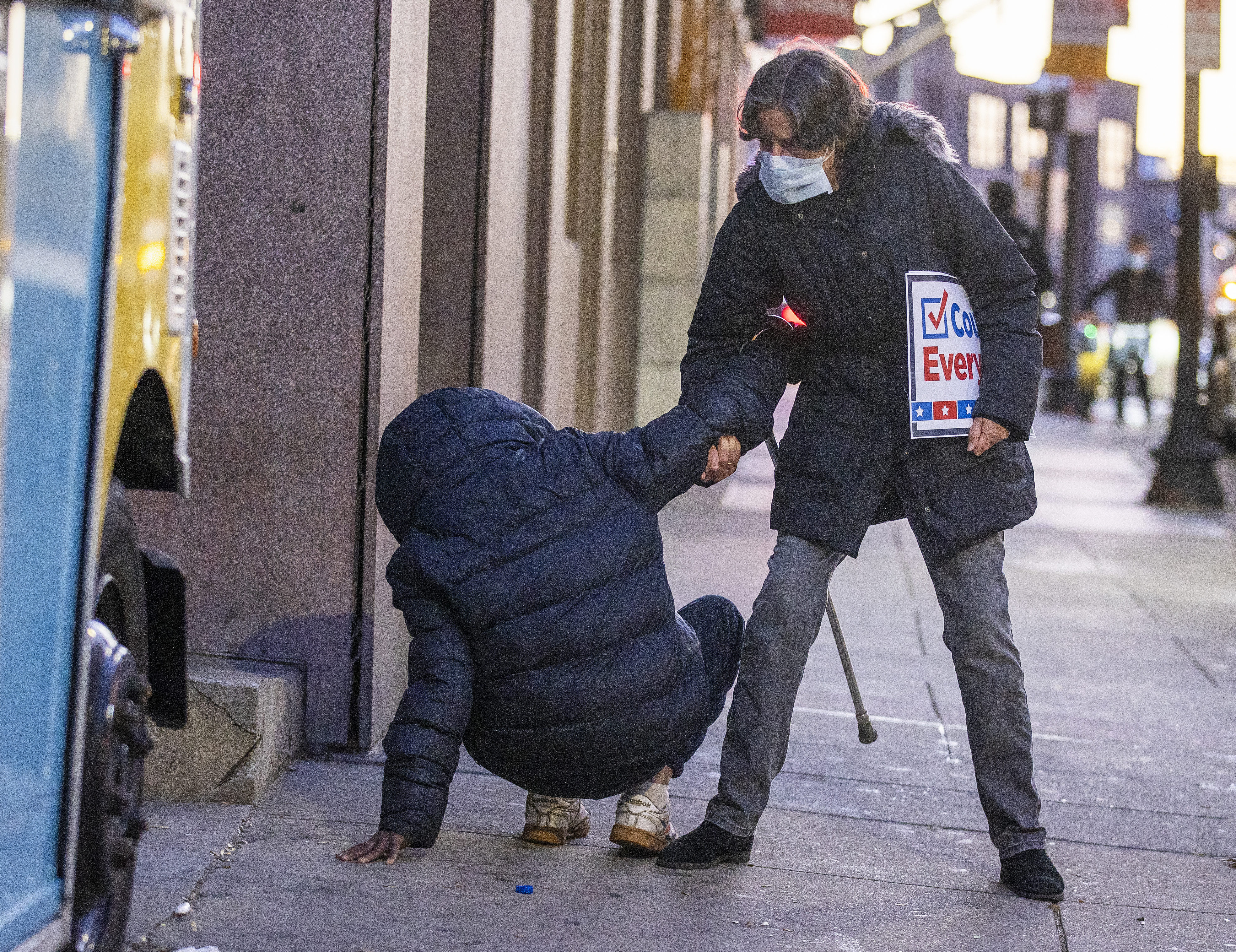 Julia Koehler of Boston on her way back from a Count Every Vote rally helps a homeless man who fell on Newbury St.