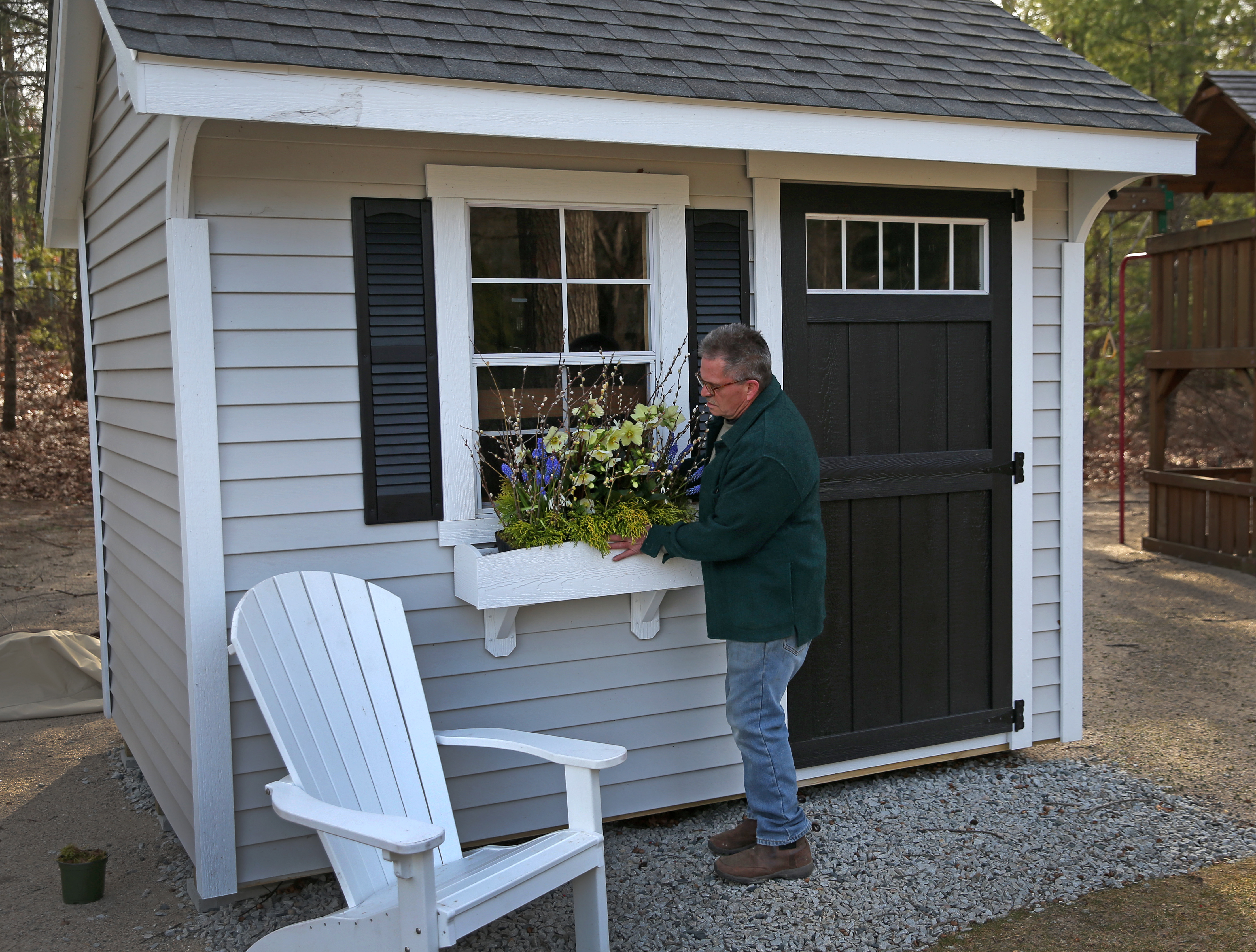 George Stanchfield works at a shed on a lakeside property in Plympton, putting plantings and flowers in a window box.