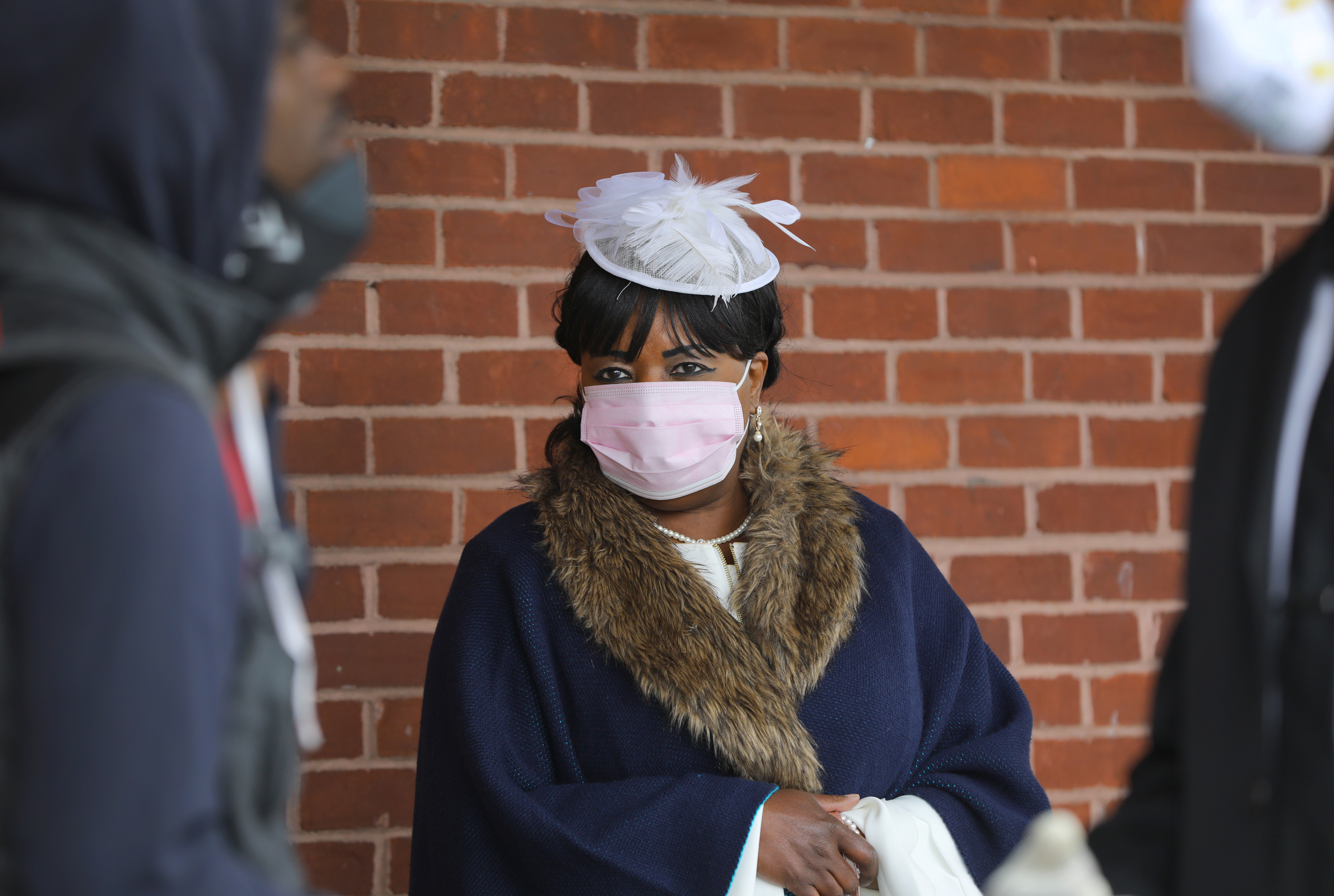 Boston, MA 4/5/2020 Deaconess Carol Thomas, of Pleasant Hill Missionary Baptist Church, stands by at the Stop & Shop in Grove Hall, while The Rev. Miniard Culpepper, hands out $10 bills to shoppers, during the coronavirus pandemic. (Pat Greenhouse/Globe Staff)