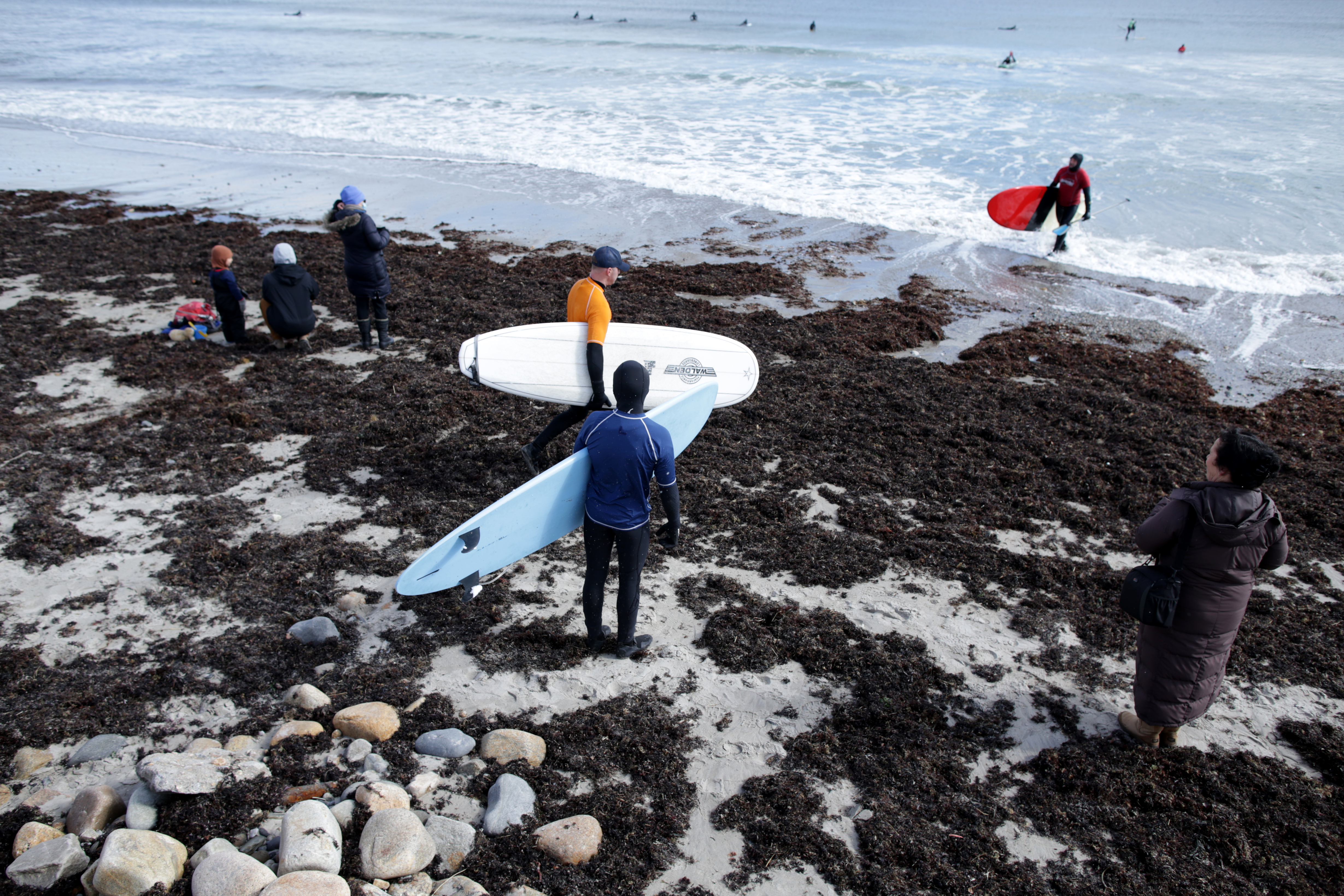 Surfers head into the water.