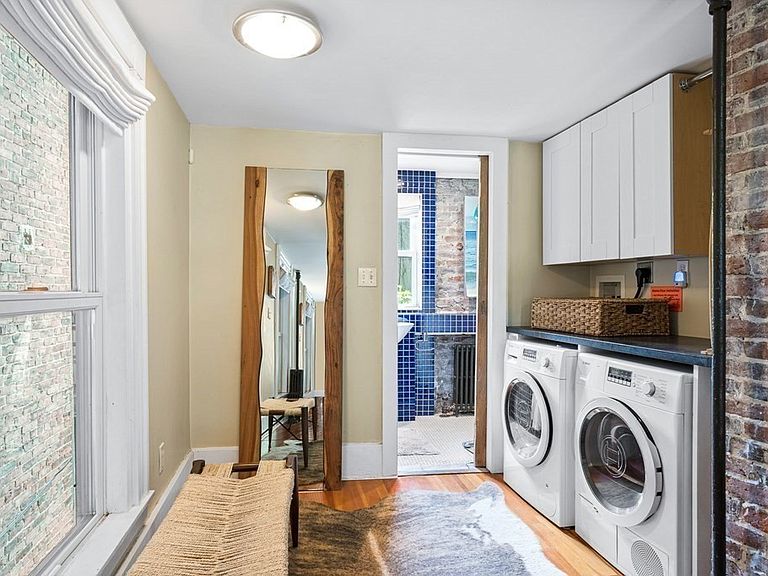 The second floor of the Skinny House contains a sitting area, a blue-tiled bathroom with a bath-shower combo, and a washer and dryer.