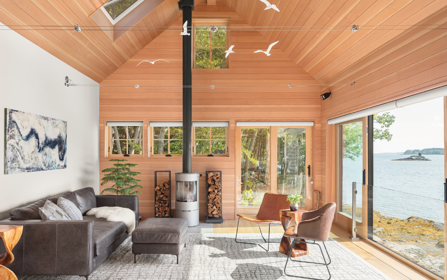The wife painted the artwork over the sofa and California-based sculptor John Perry made the porcelain seagulls suspended from the ceiling. The architects positioned the wood stove so that the chimney pipe would not block the window.