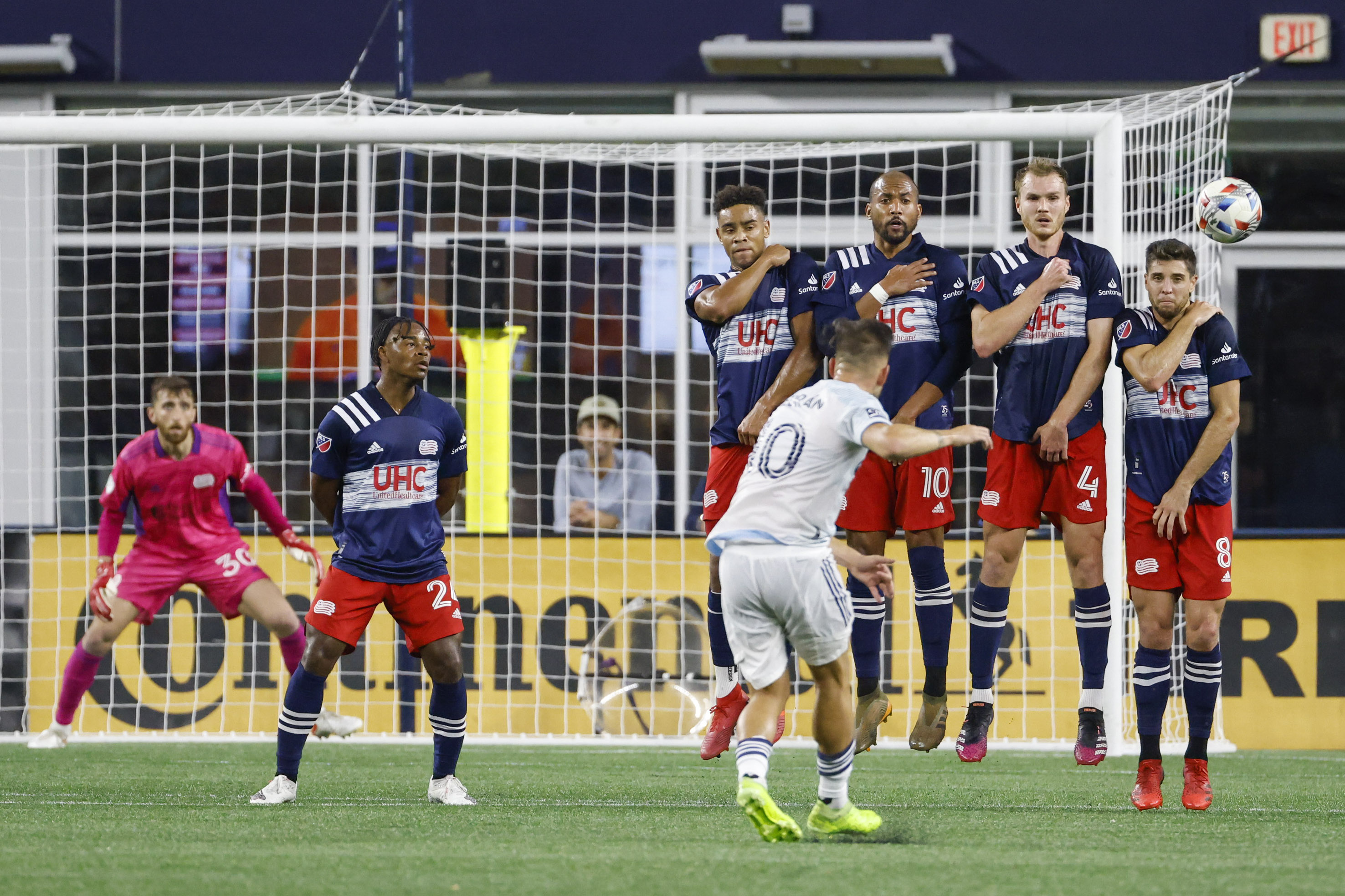 Chicago Fire midfielder Alvaro Medran curves a ball past a defensive line anchored by Revolution defender Matthew Polster (No. 8).
