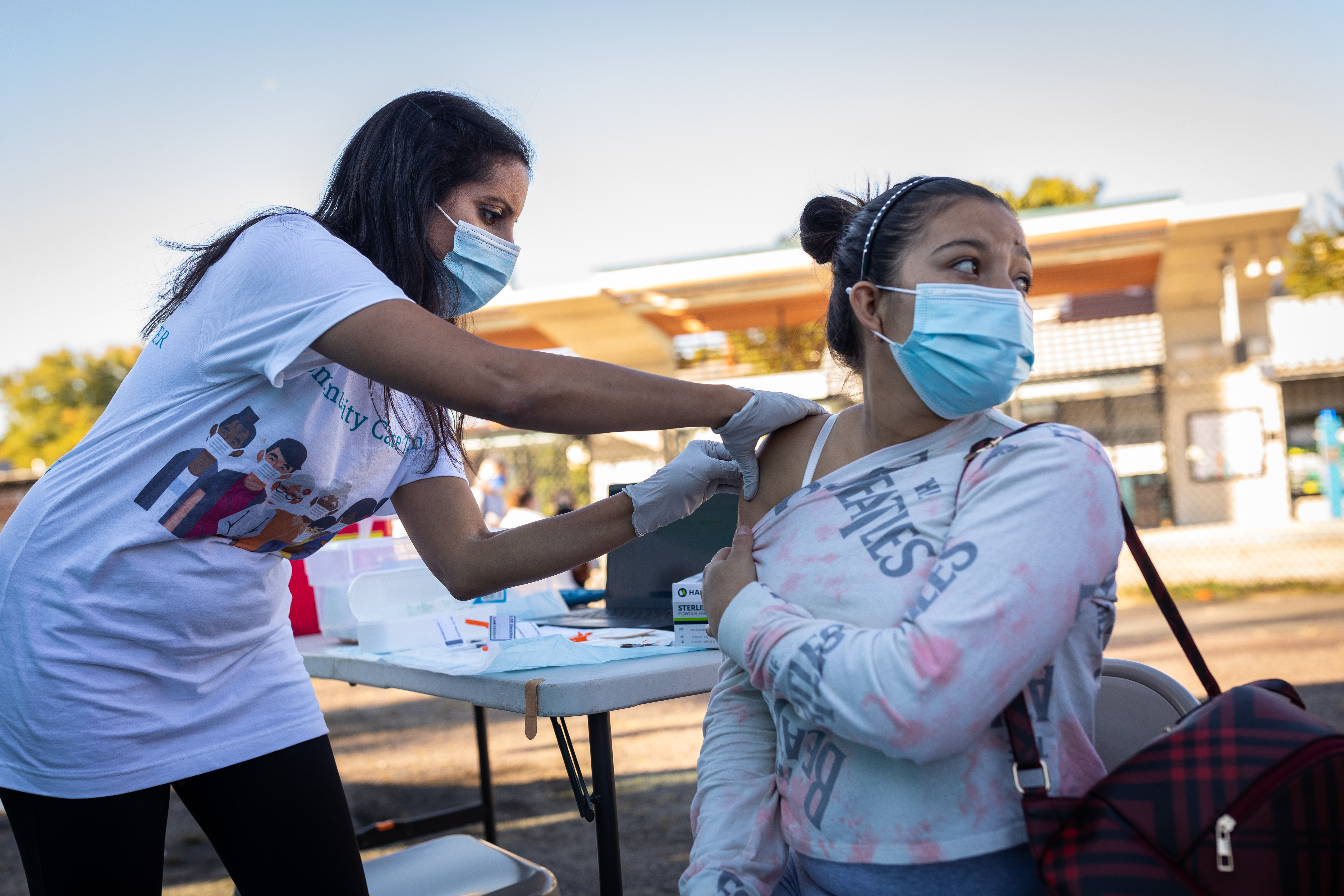 (L-R) Priya Sarin Gupta prepares to give a COVID-19 vaccine to Maria Del Carmen, 21, outside an MGH vaccination van during a mini-festival for teens at the La Colaborativa food pantry in Chelsea on Oct. 06, 2021.