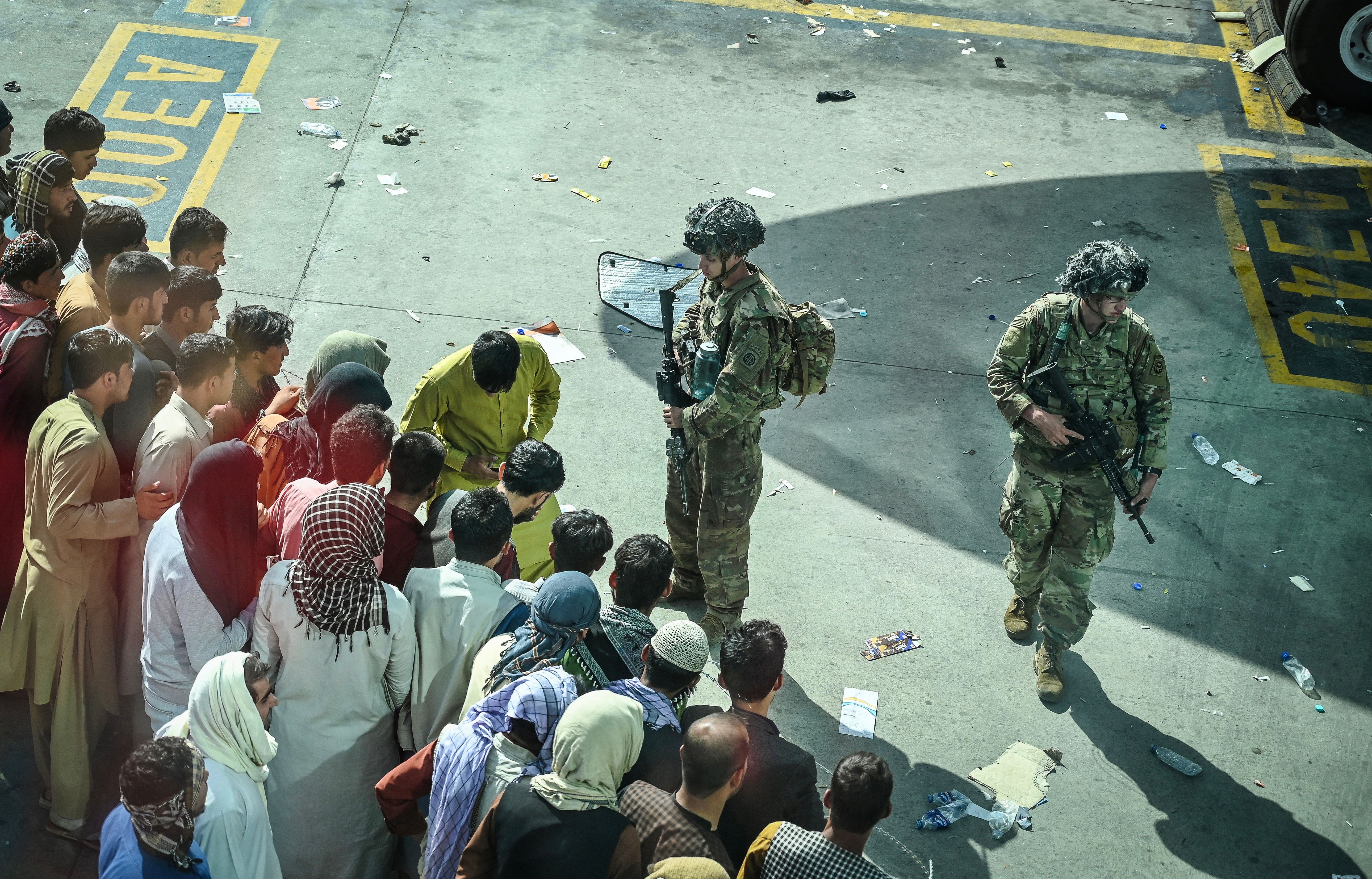 US soldiers stand guard as Afghan people wait at the Kabul airport.