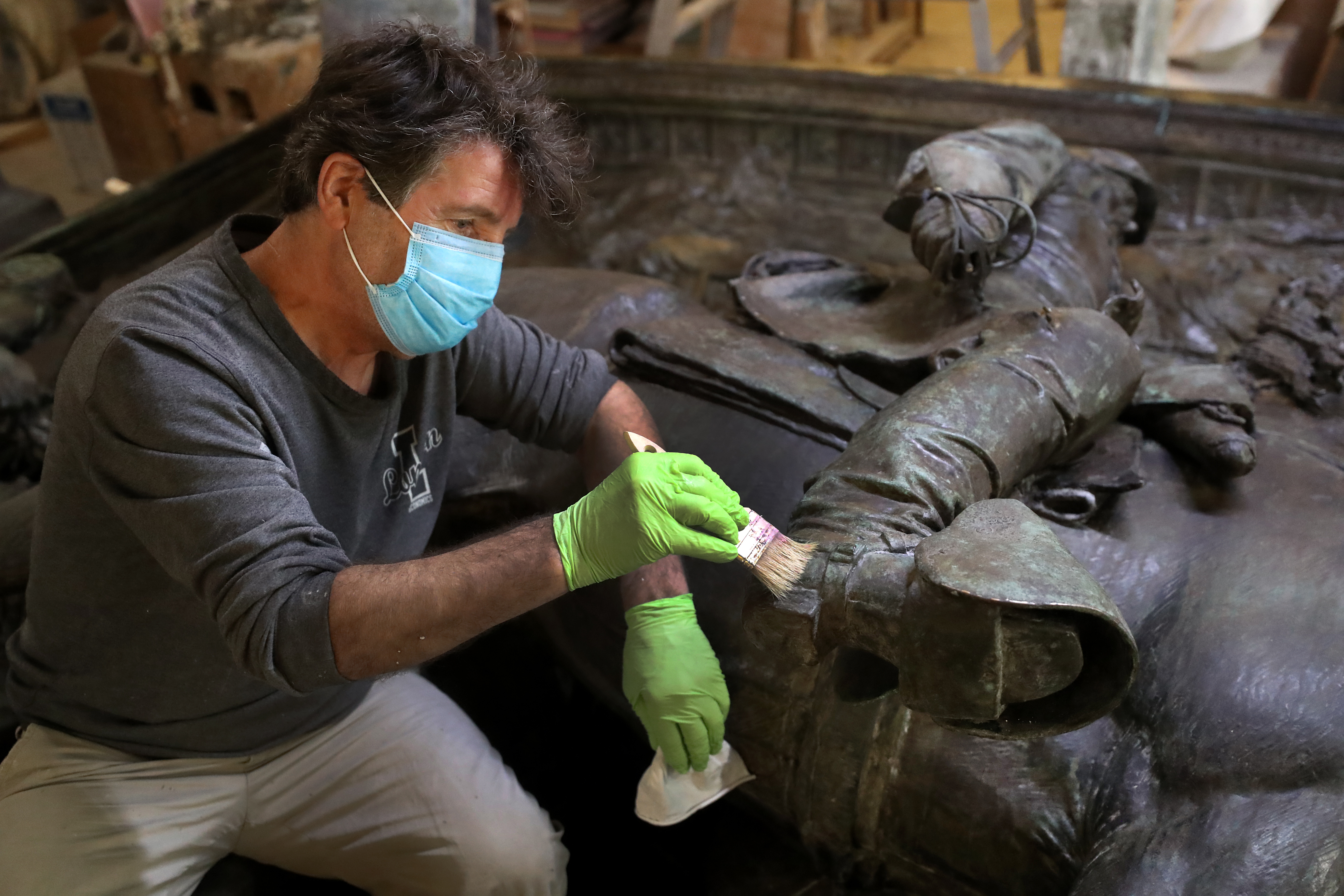 Luciano Caruso, an employee with Skylight Studios in Woburn, applies a stripper to the bottom of Colonel Shaw's boot.