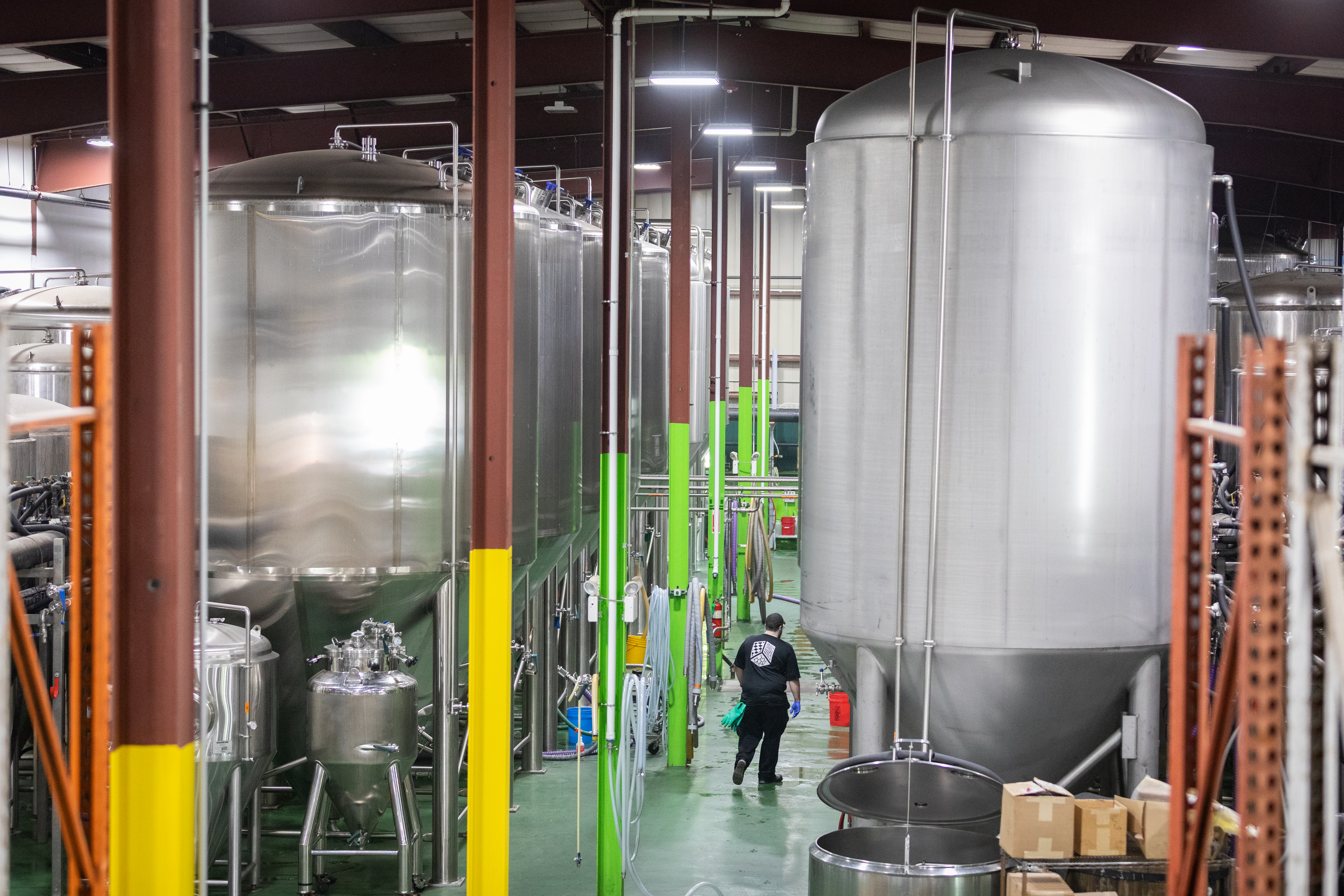 A worker walks past storage tanks inside Jack’s Abby Craft Lagers in Framingham.