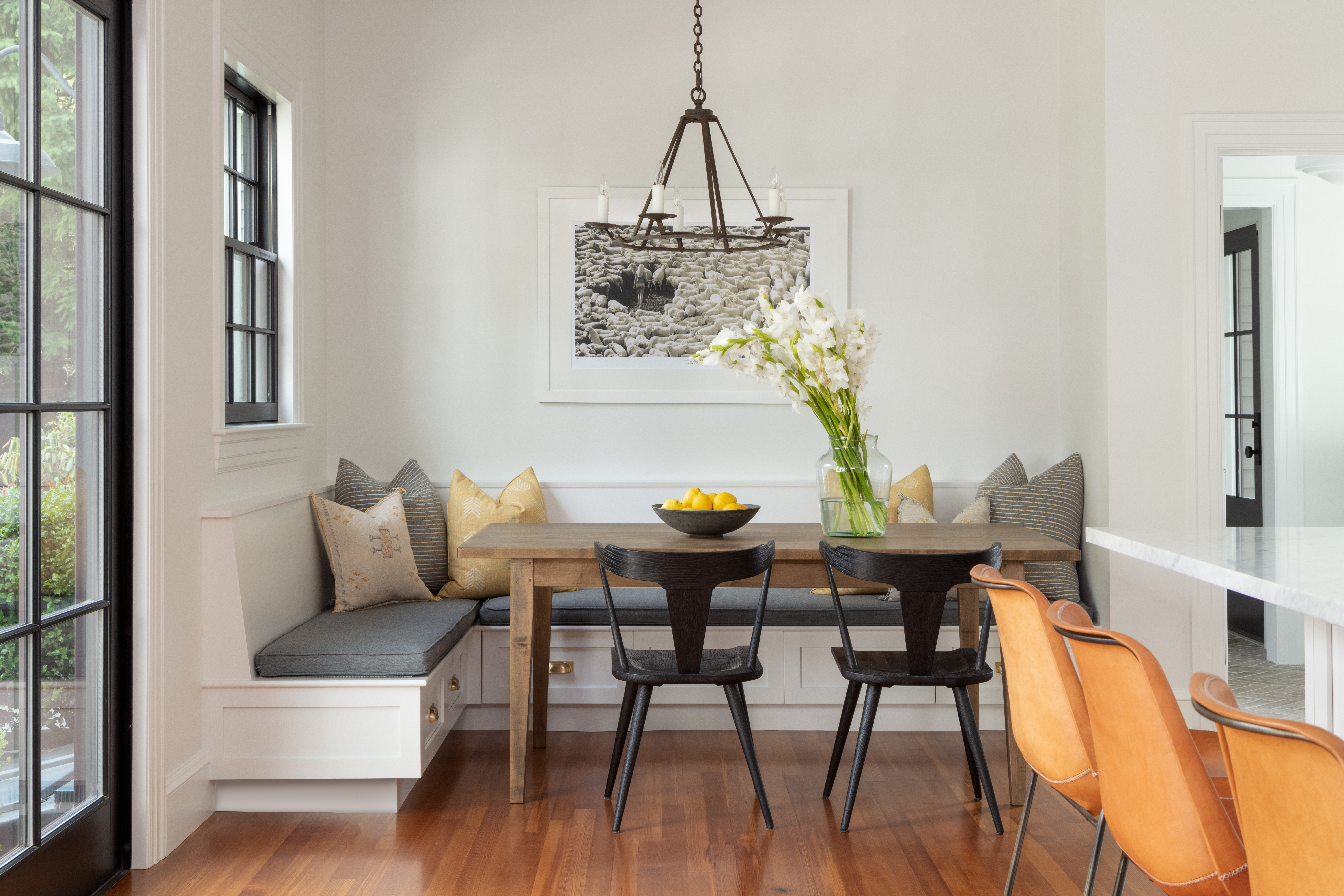 A photograph by Michael Joseph hangs in the breakfast nook, adding modern edge to the rustic table, Old World-style chandelier, and pillows made from global textiles.