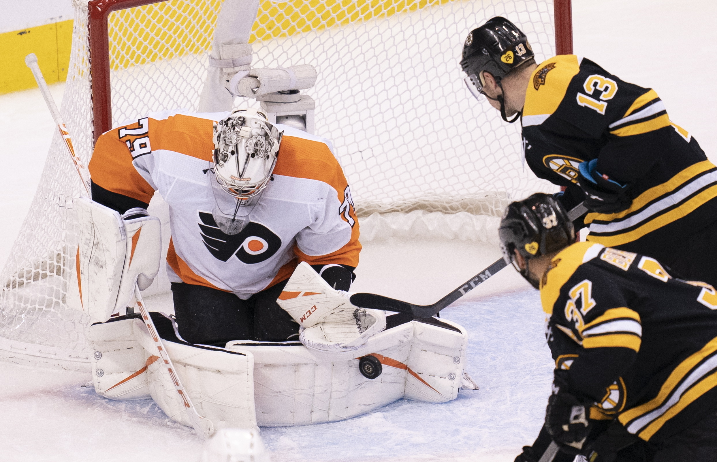 Philadelphia goaltender Carter Hart makes a save as Charlie Coyle and Patrice Bergeron close in during third period of Sunday's game.