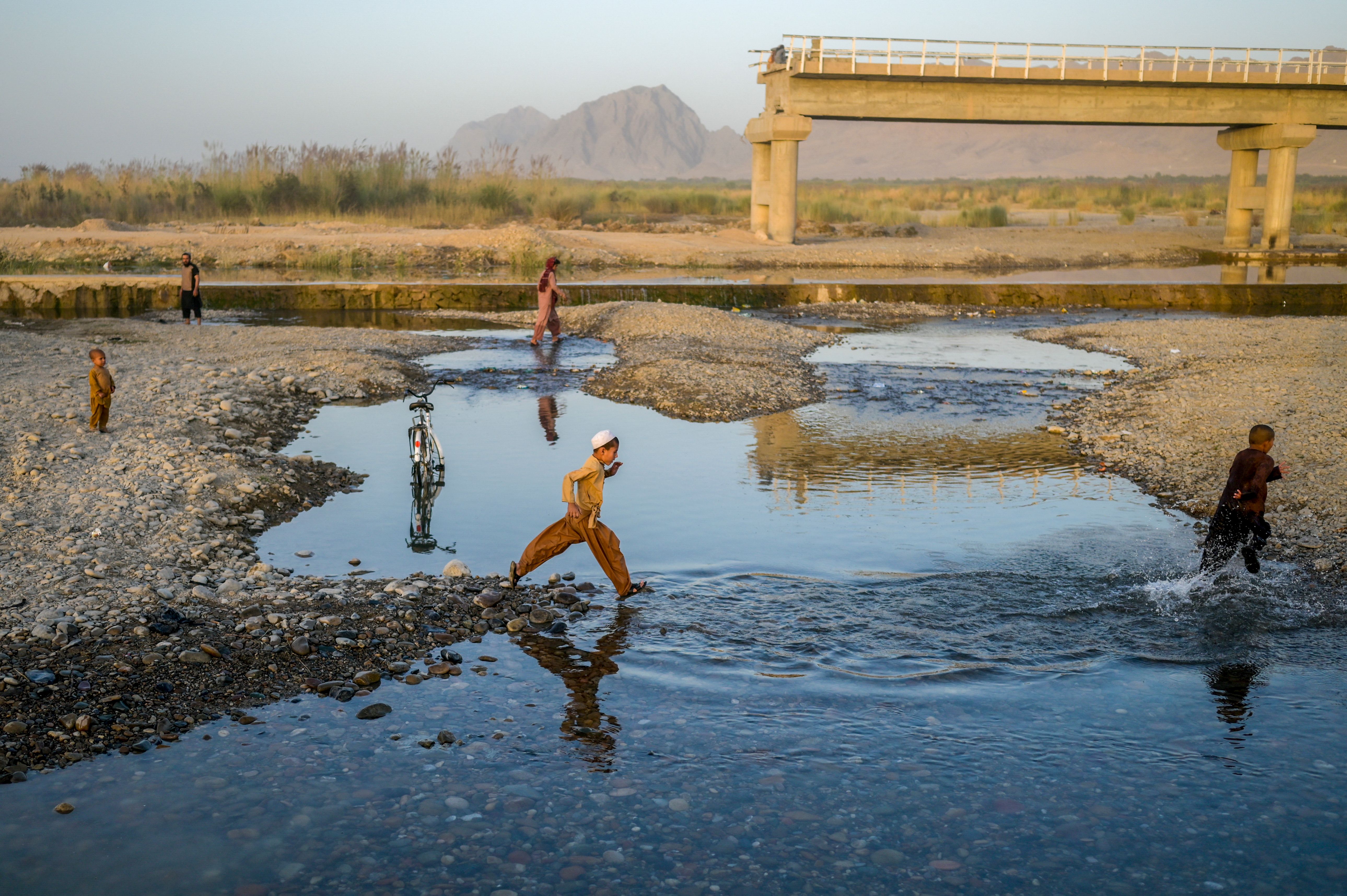 Children ran across a riverbed, near a damaged bridge in Kandahar on Sept 23.