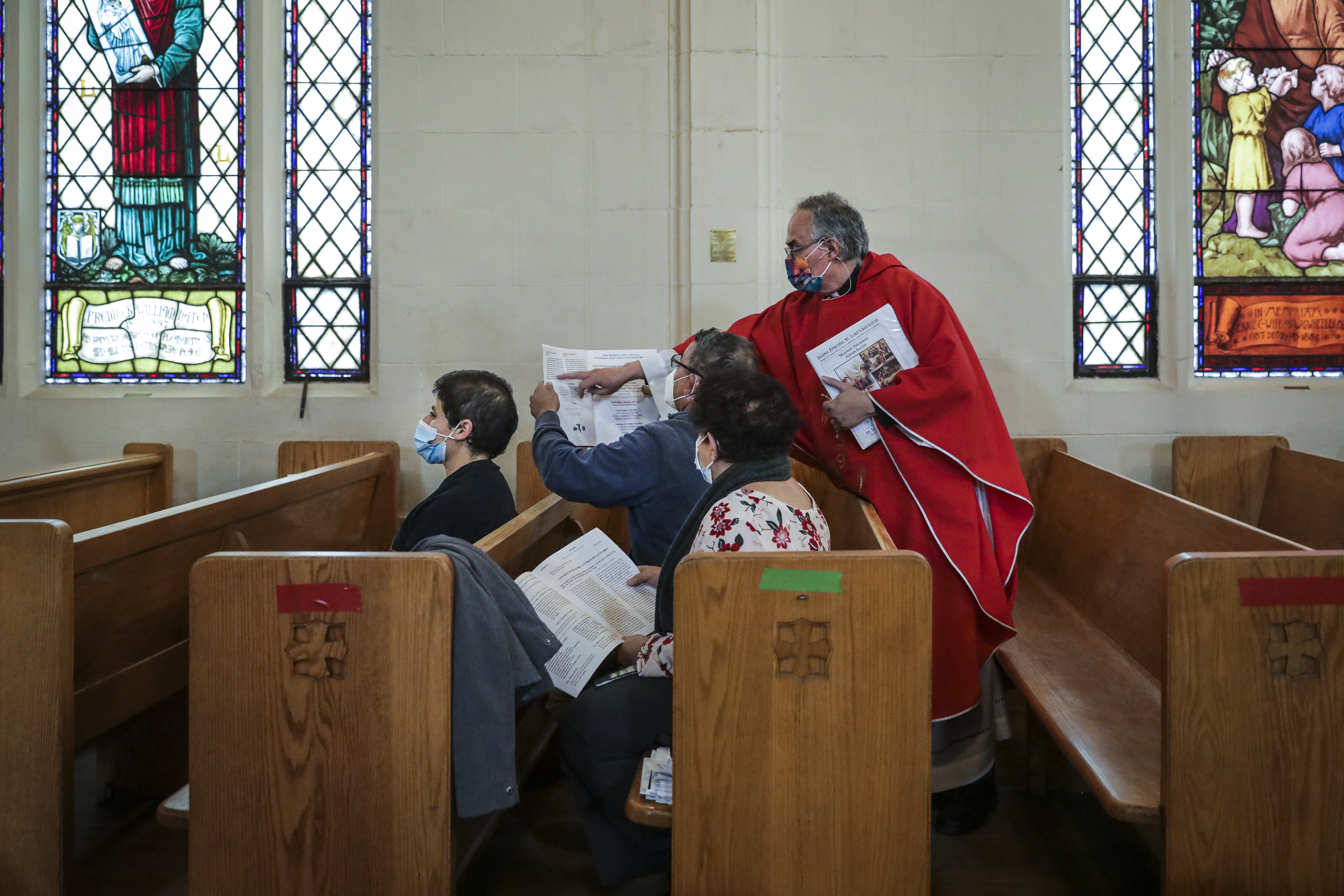 The Rev. Edgar Gutierrez-Duarte of St. Luke-San Lucas in Chelsea points to where congregation member Vicente Perez should read as Perez sat with his family during Thursday's service.