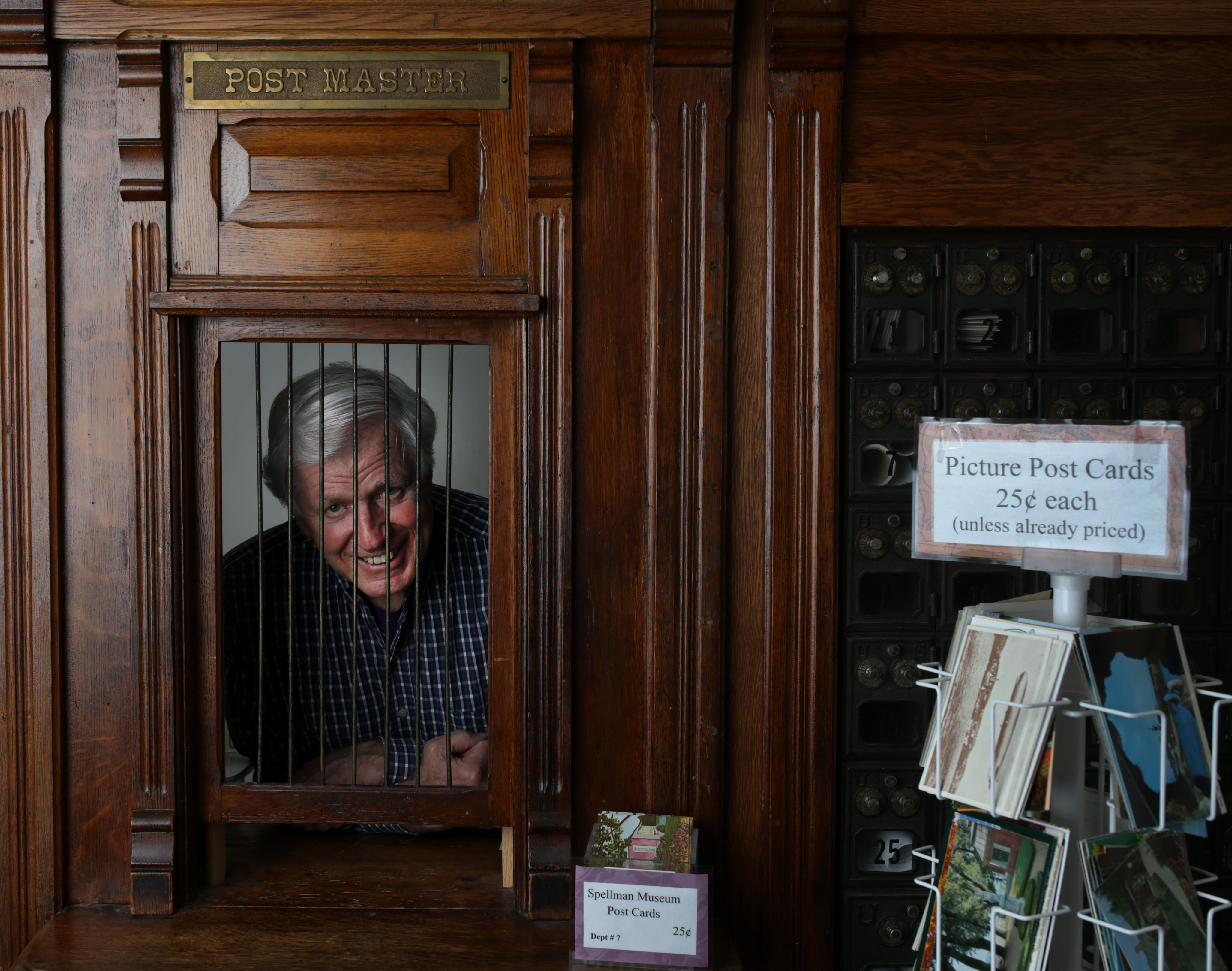 Joseph W. Mullin, executive director of the Spellman Museum of Stamps & Postal History in Weston, looks out of a facade that was taken from a 19th-century post office that’s now a part of the museum’s store.