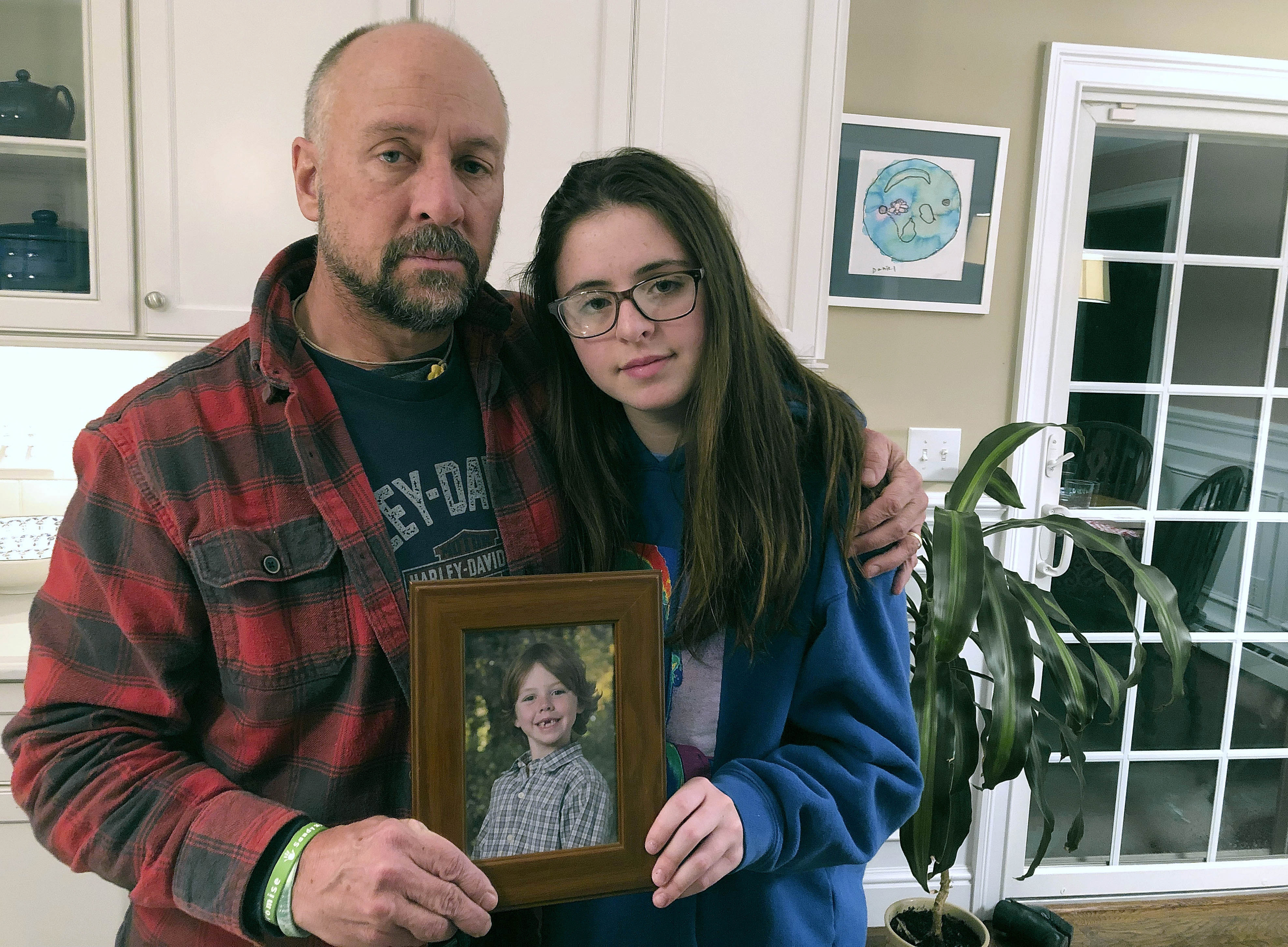 Mark Barden and his daughter Natalie Barden held a photograph of Natalie's late brother, Daniel, at their home in Newtown, Conn. on Dec. 3, 2019.