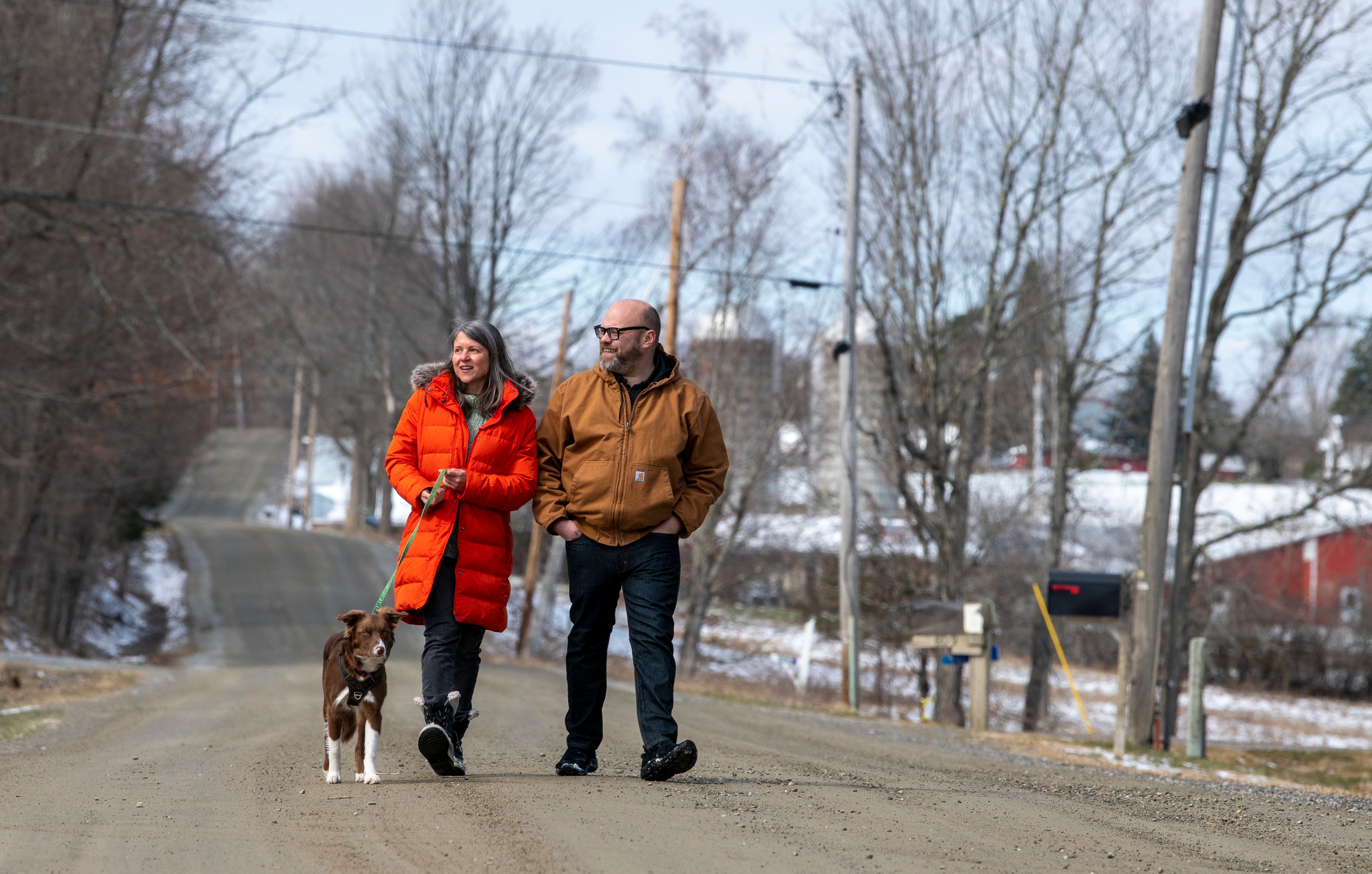 Adam Davidson and Jen Banbury walk with their border collie, Feather, in Charlotte, Vt.