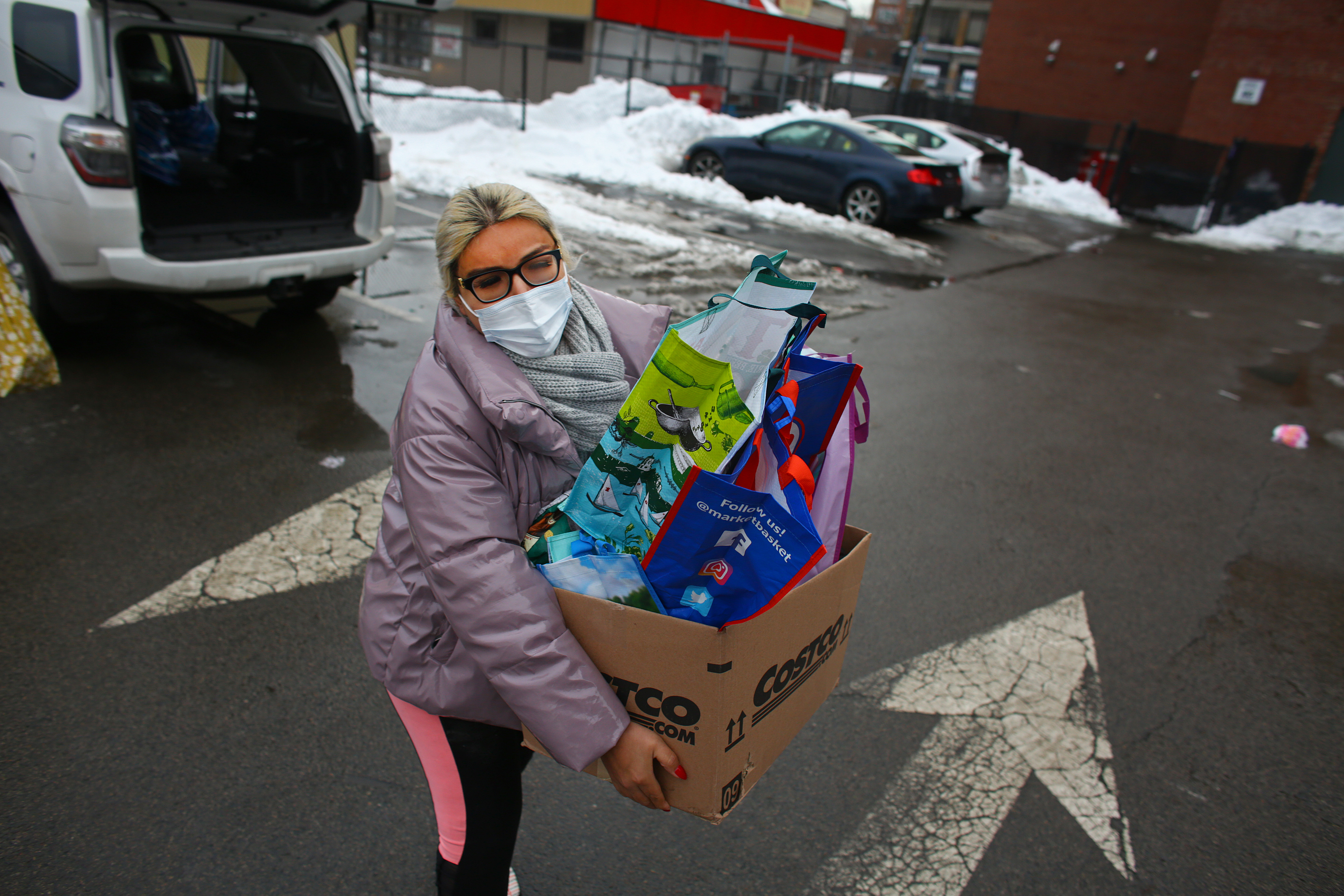 Alex Bradford and Megan Greeley, not shown, hand off gifts to a representative of Nuestra Comunidad in Roxbury. Housing resource program manager Selena Rodriguez accepts the gifts in an exchange between the two vehicles.