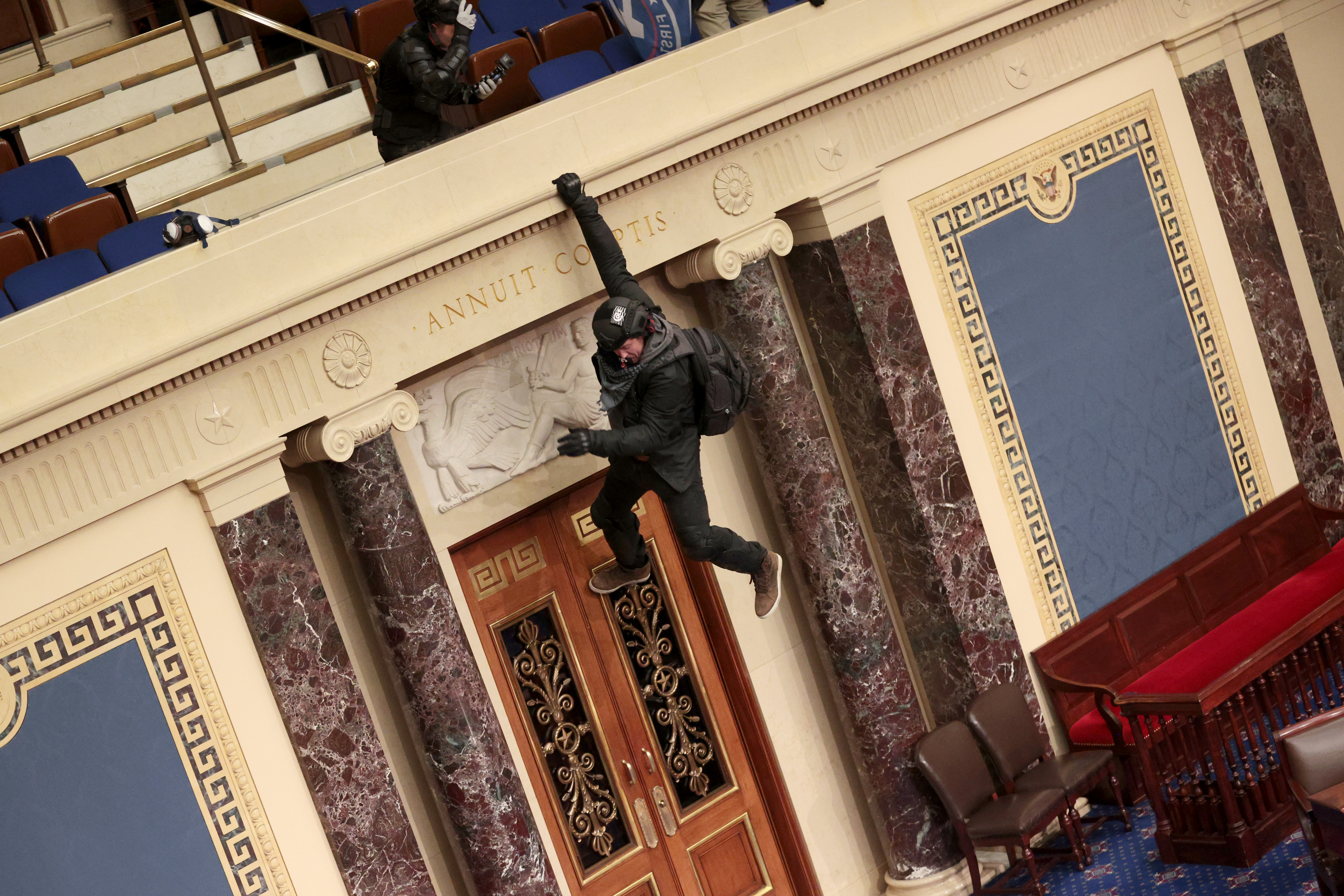 A Trump supporter is seen hanging from the balcony in the Senate Chamber.