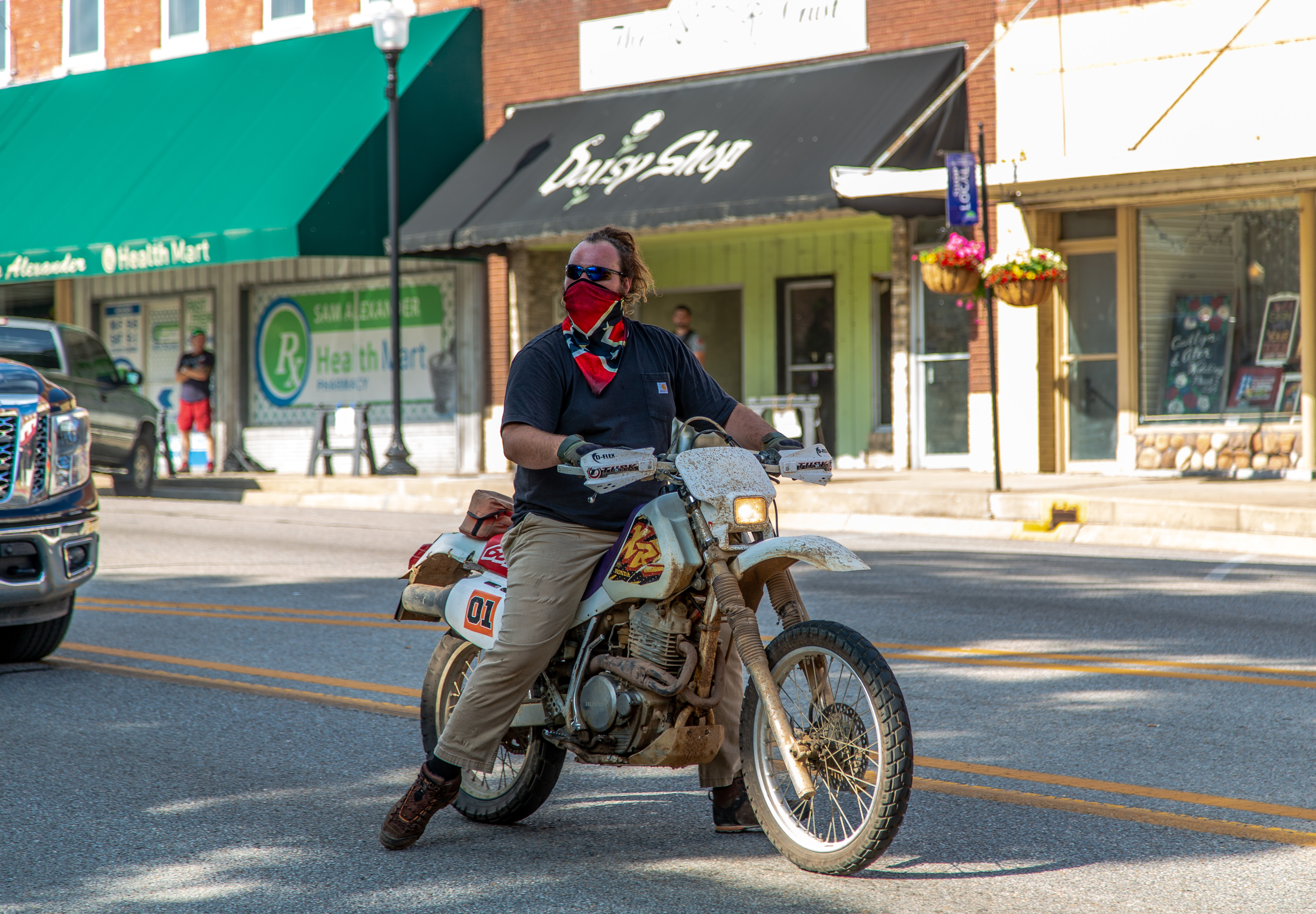A man riding a dirt bike and wearing a rebel flag bandana pulled up over his face stared down Black Lives Matter protesters in the town square.