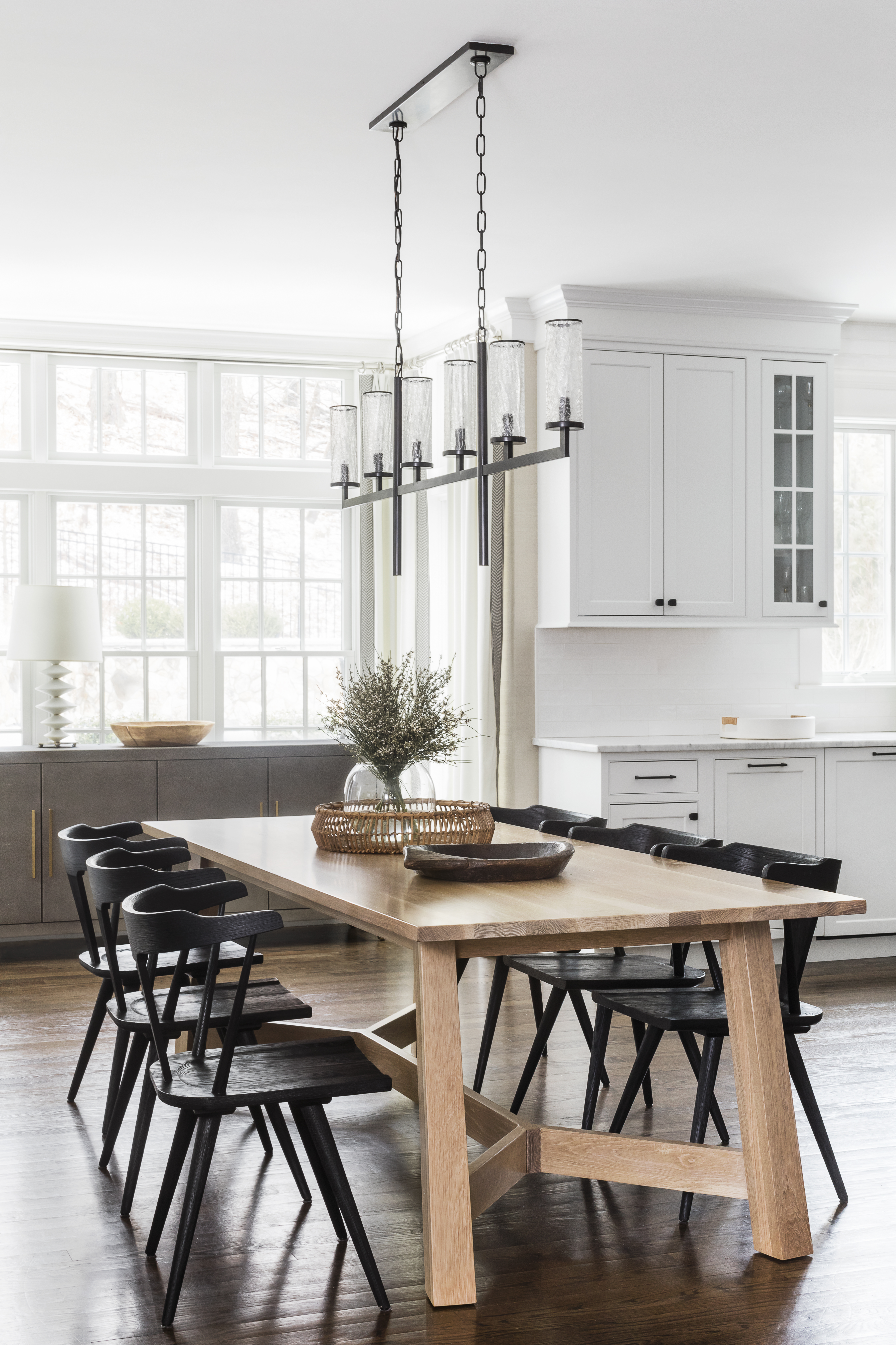 Modern Windsor chairs in the dining room are sculptural yet spare, as is the linear chandelier with crackled glass shades designed by Kelly Wearstler for Visual Comfort. “We love that the light is visible in the living room mirror and from the entry,” designer Liza Kugeler says.