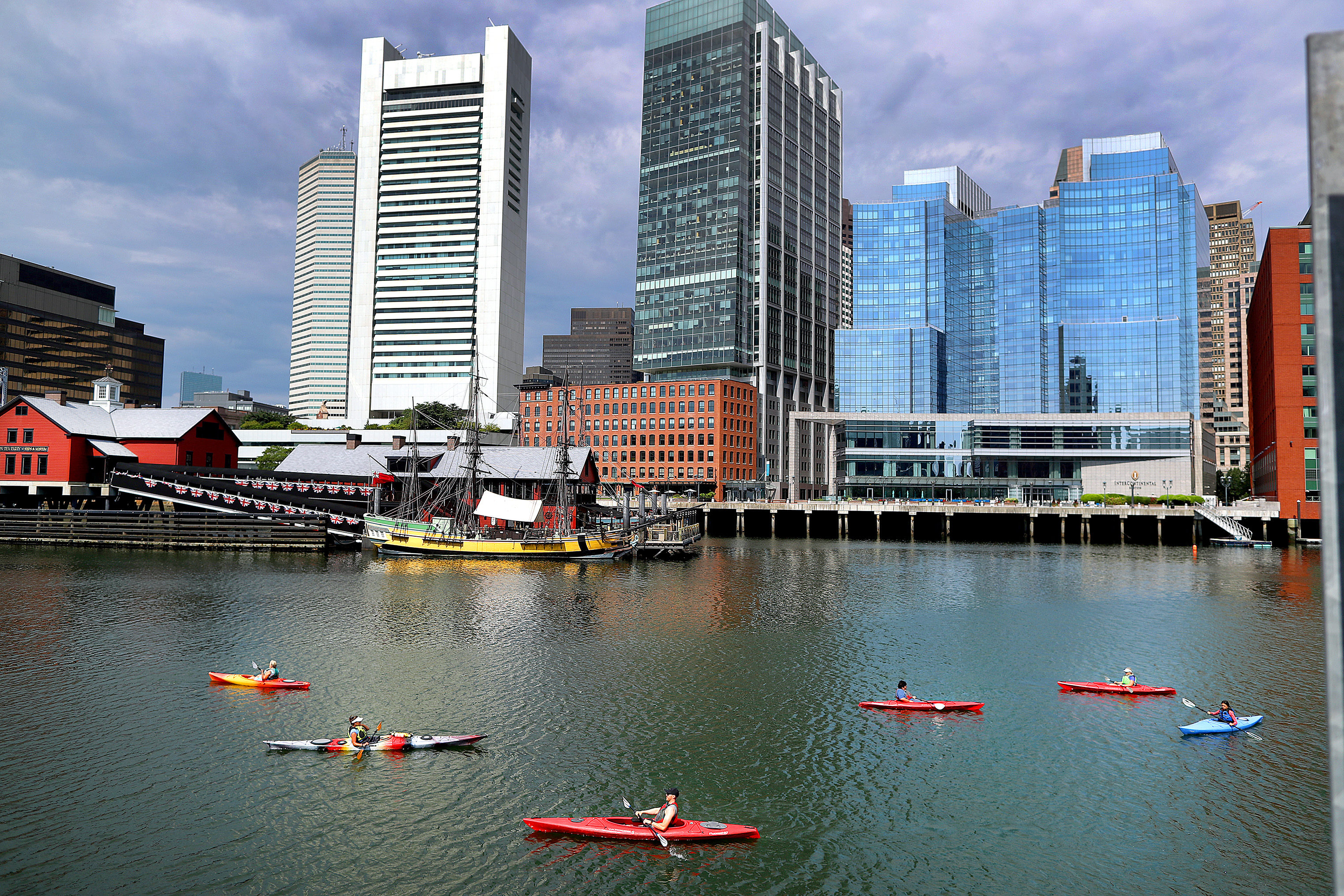 Kayakers paddle along the Fort Point Channel as the Boston Sykline forms the backdrop.