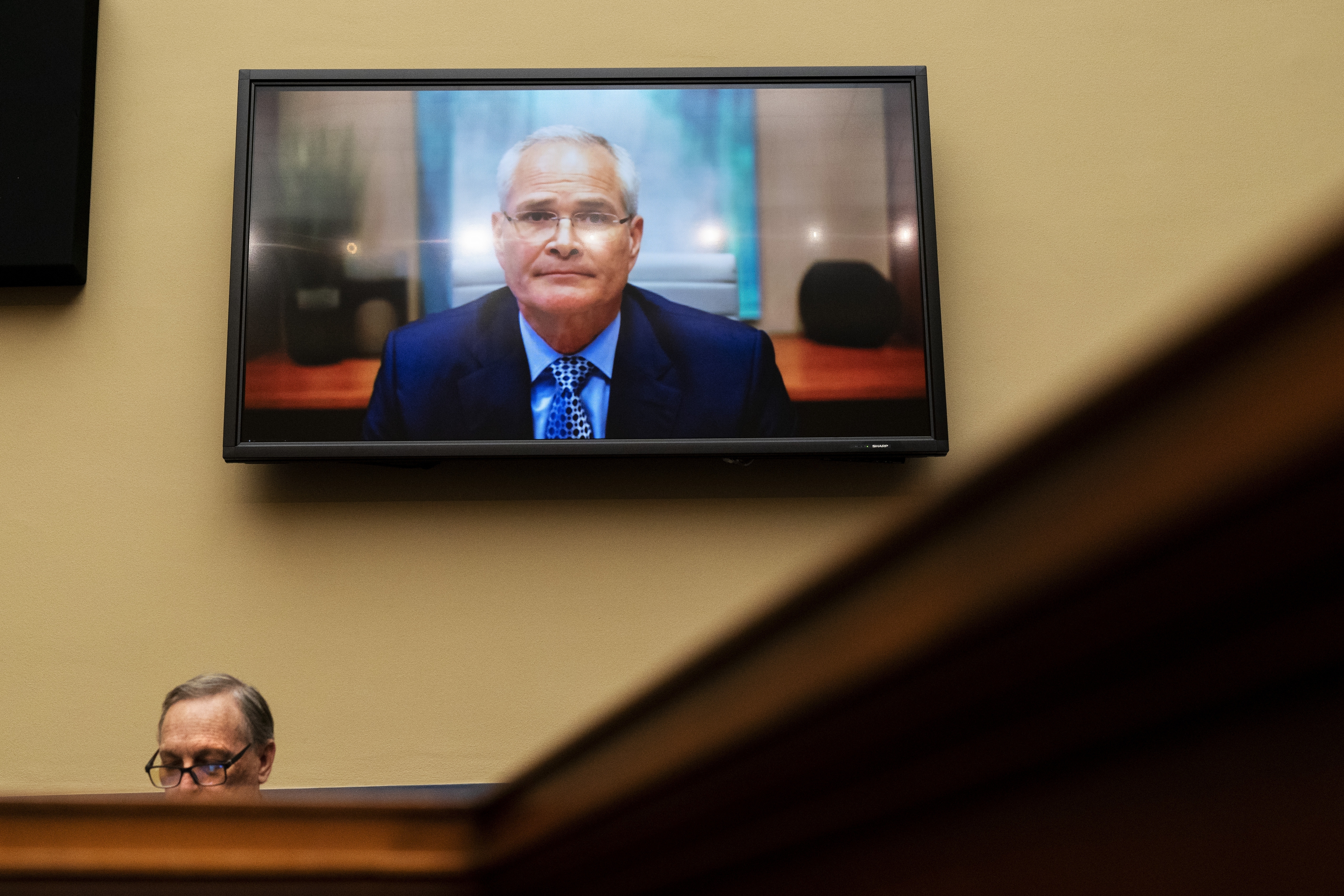 Darren Woods, CEO of ExxonMobil, testifies via video conference during a House Committee on Oversight and Reform, on Oct. 28, with Representative Ralph Norman in the foreground, on Capitol Hill, in Washington.