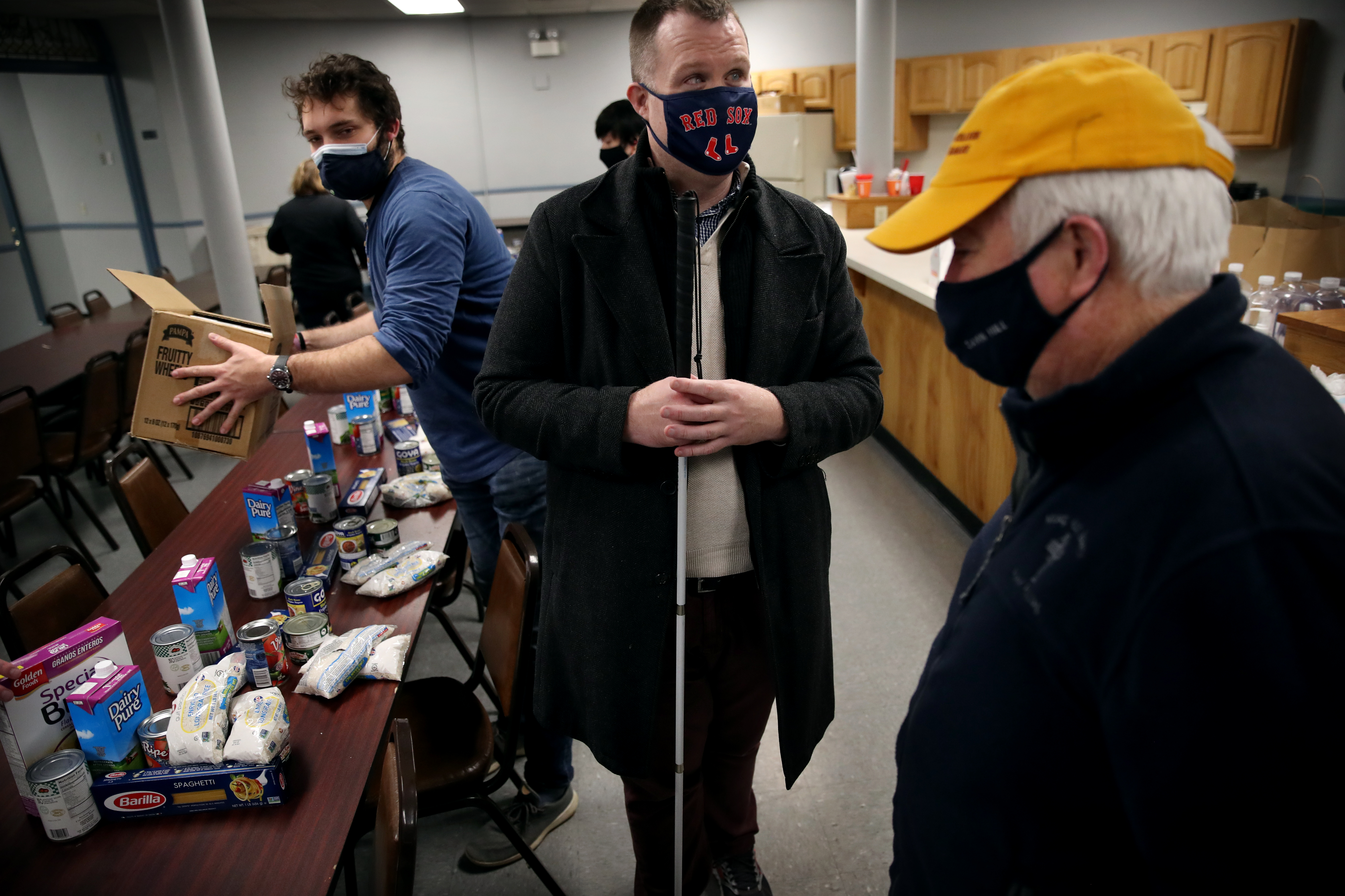 Boston City Council candidate Alex Gray, center, talks with Roger Croke, right, while volunteering at the Mary Ann Brett Food Pantry.