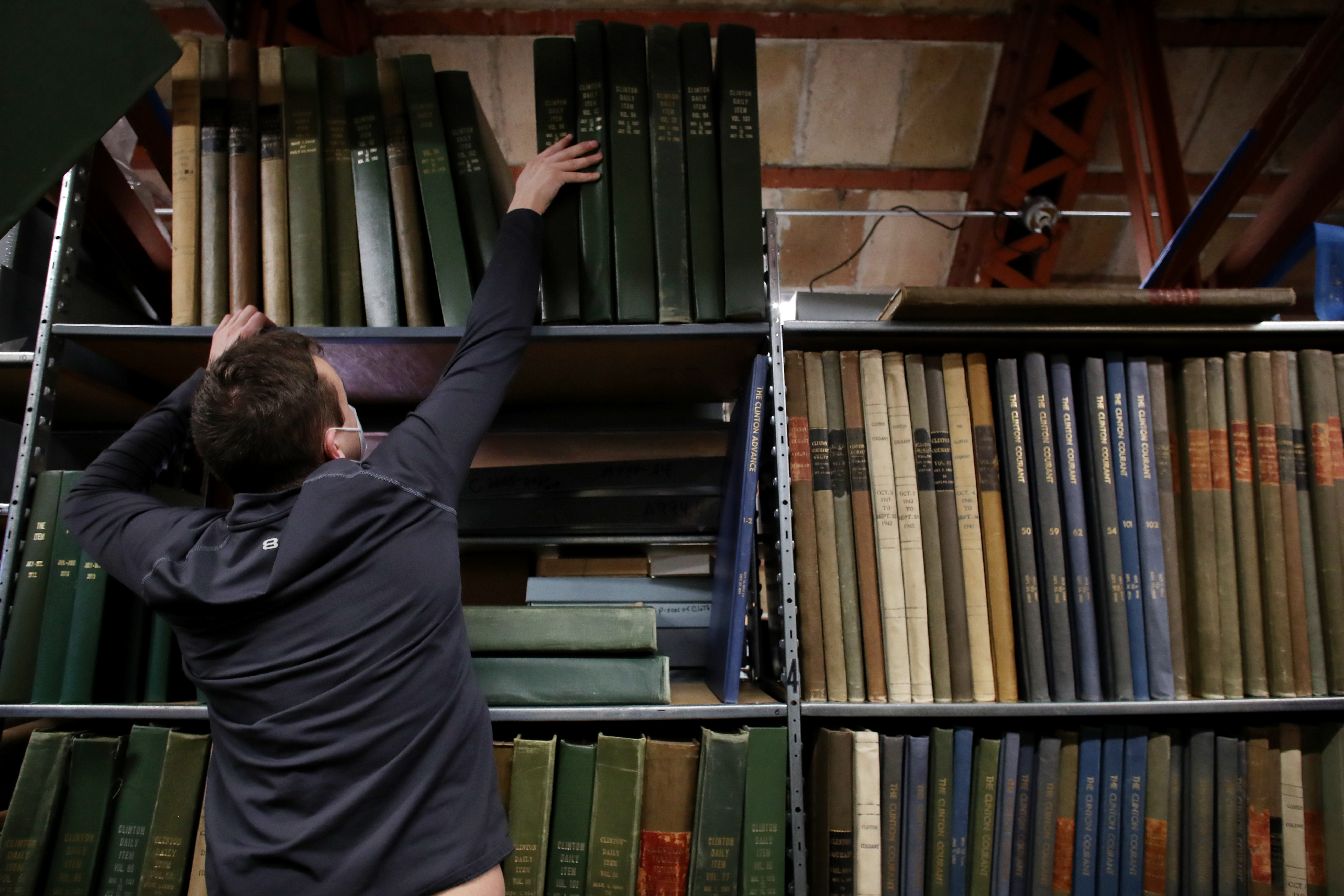 Bodie Aurin placed a volume of the Clinton Daily Item on a shelf at the Clinton Historical Society in Clinton.