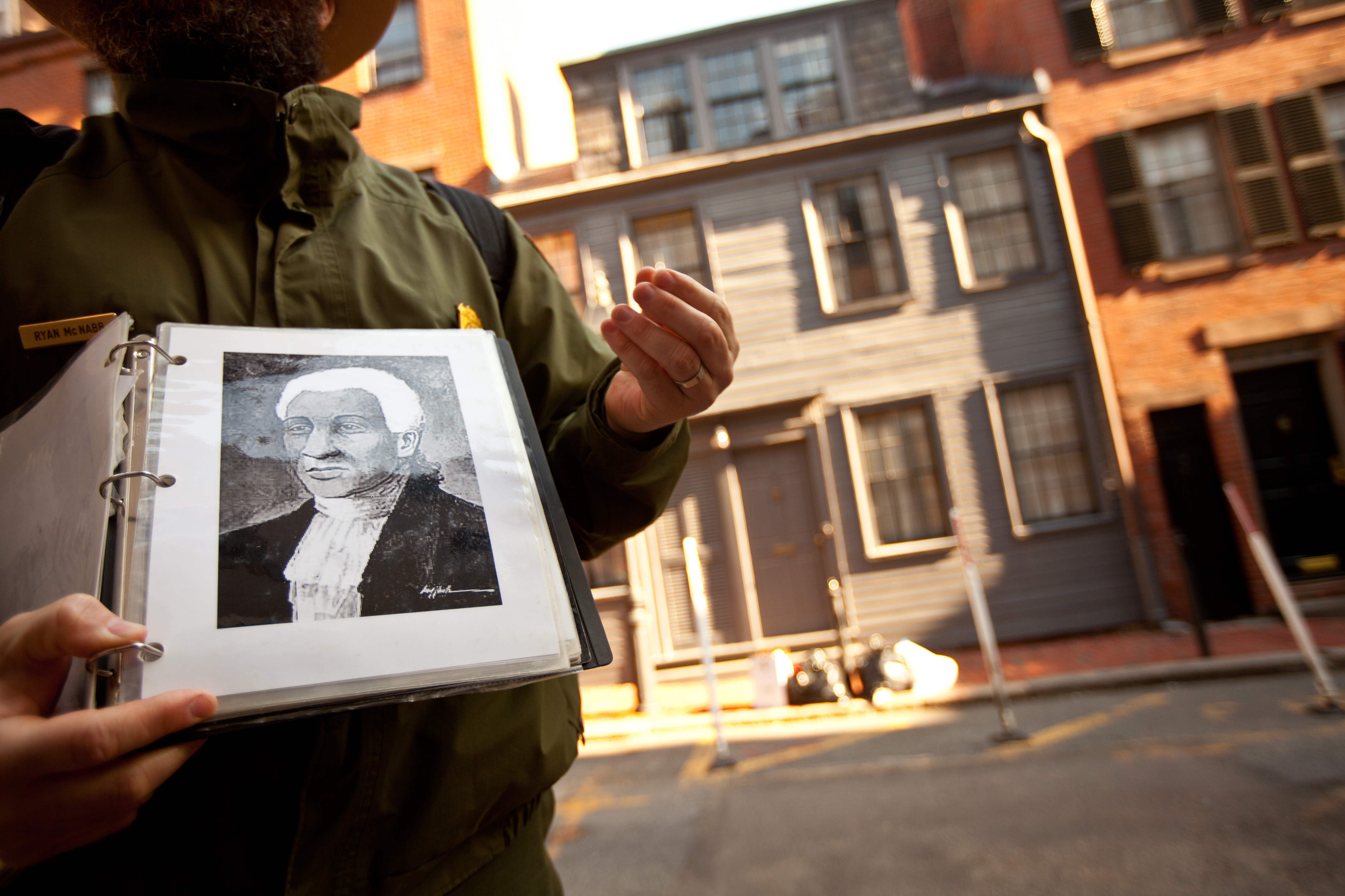 A park ranger holds a photo of Prince Hall in front of the George Middleton House on Beacon Hill. Hall founded the Prince Hall Masons, the oldest and largest predominantly Black fraternity in the nation.