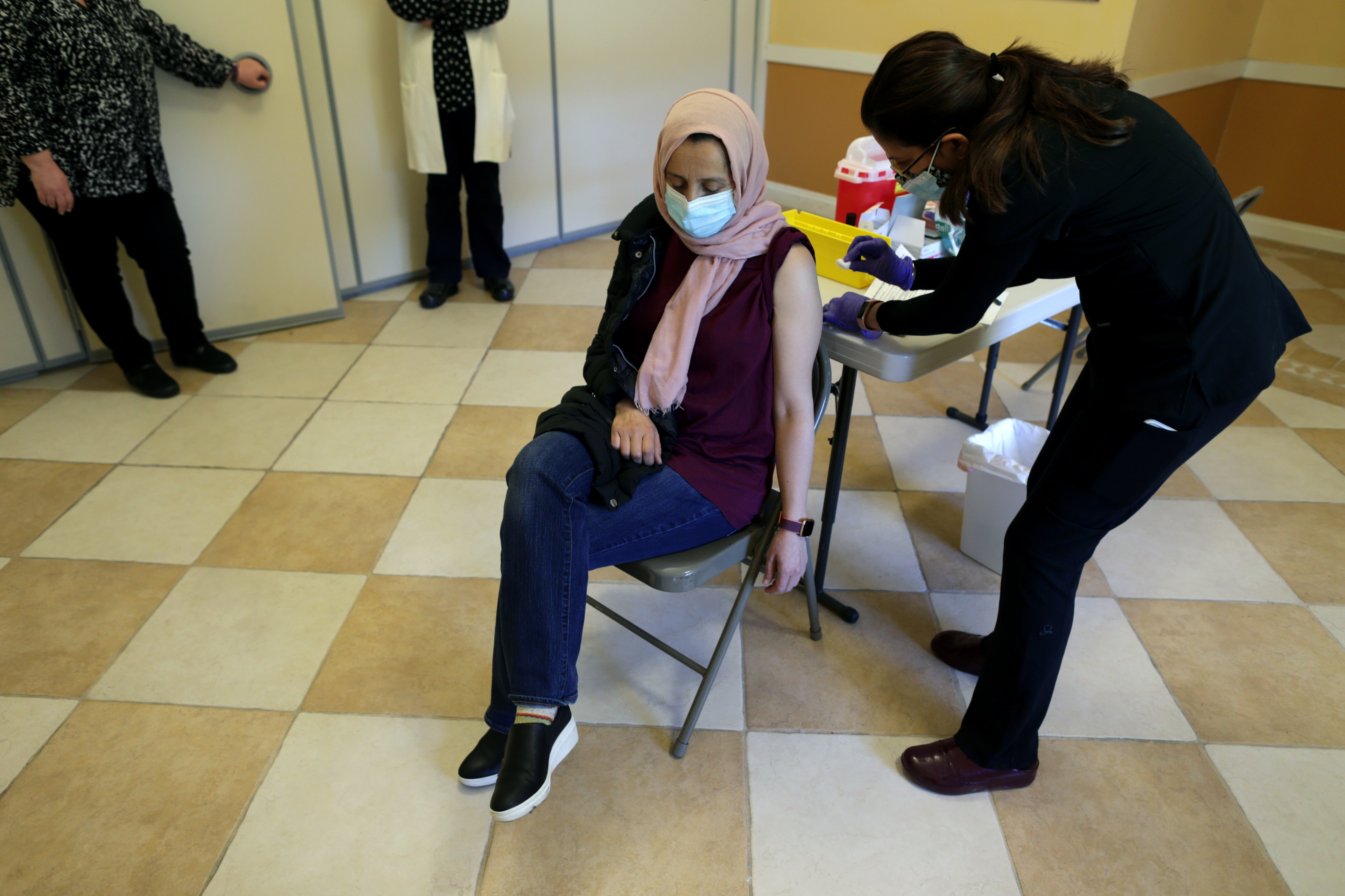 Habiba Dirrane received her first Pfizer Covid-19 vaccination shot from Dr. Saima Khan, right , at the The Islamic Center in Wayland vaccination clinic.