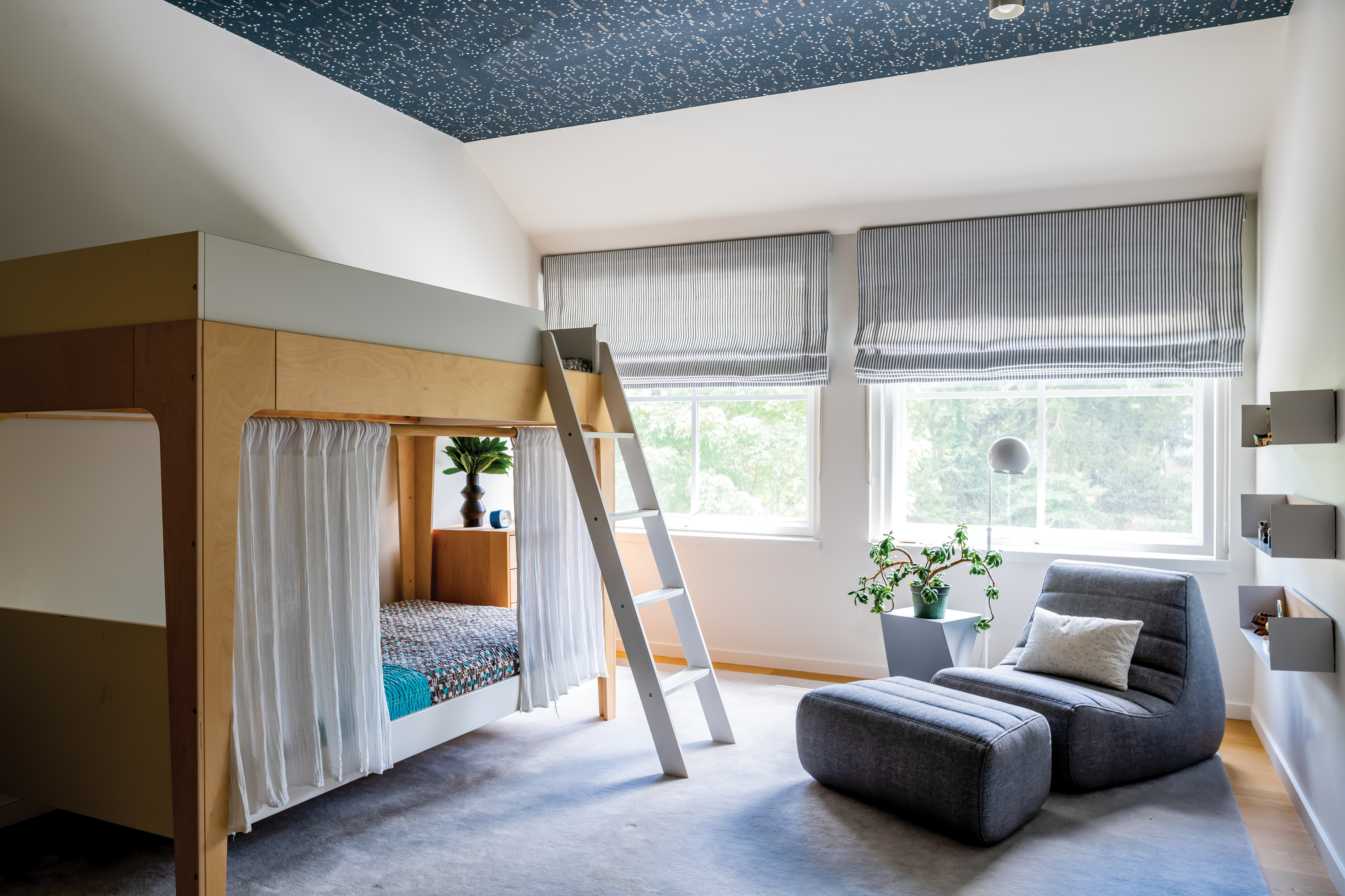 In the son’s room, one section of a three-piece Saparella sofa by Ligne Roset sits beside Ethnicraft wall-hung shelves. The bunk bed is by Oeuf and the ceiling paper is Northern Hemisphere by Ralph Lauren.