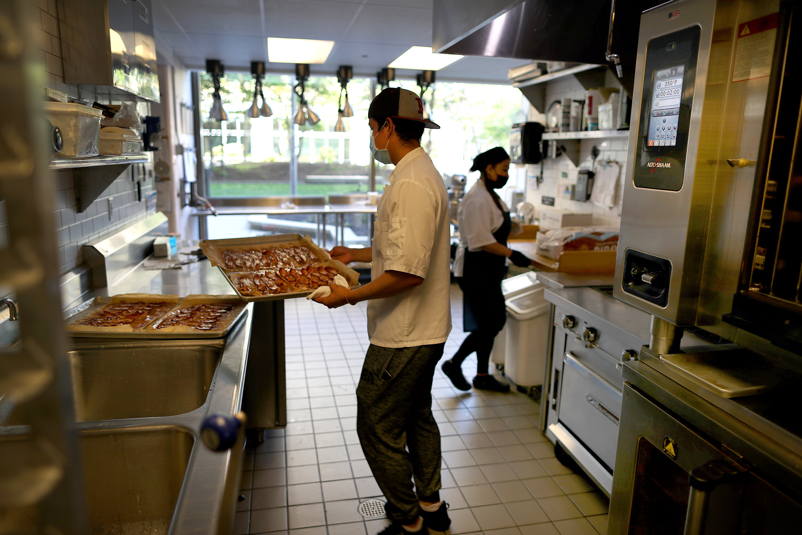 Porto Restaurant is trying to figure out how to deal with social distancing and COVID-19 when it opens up, as designs are in the works. Cook Wilfredo Guerrero takes a tray of bacon out of the oven.