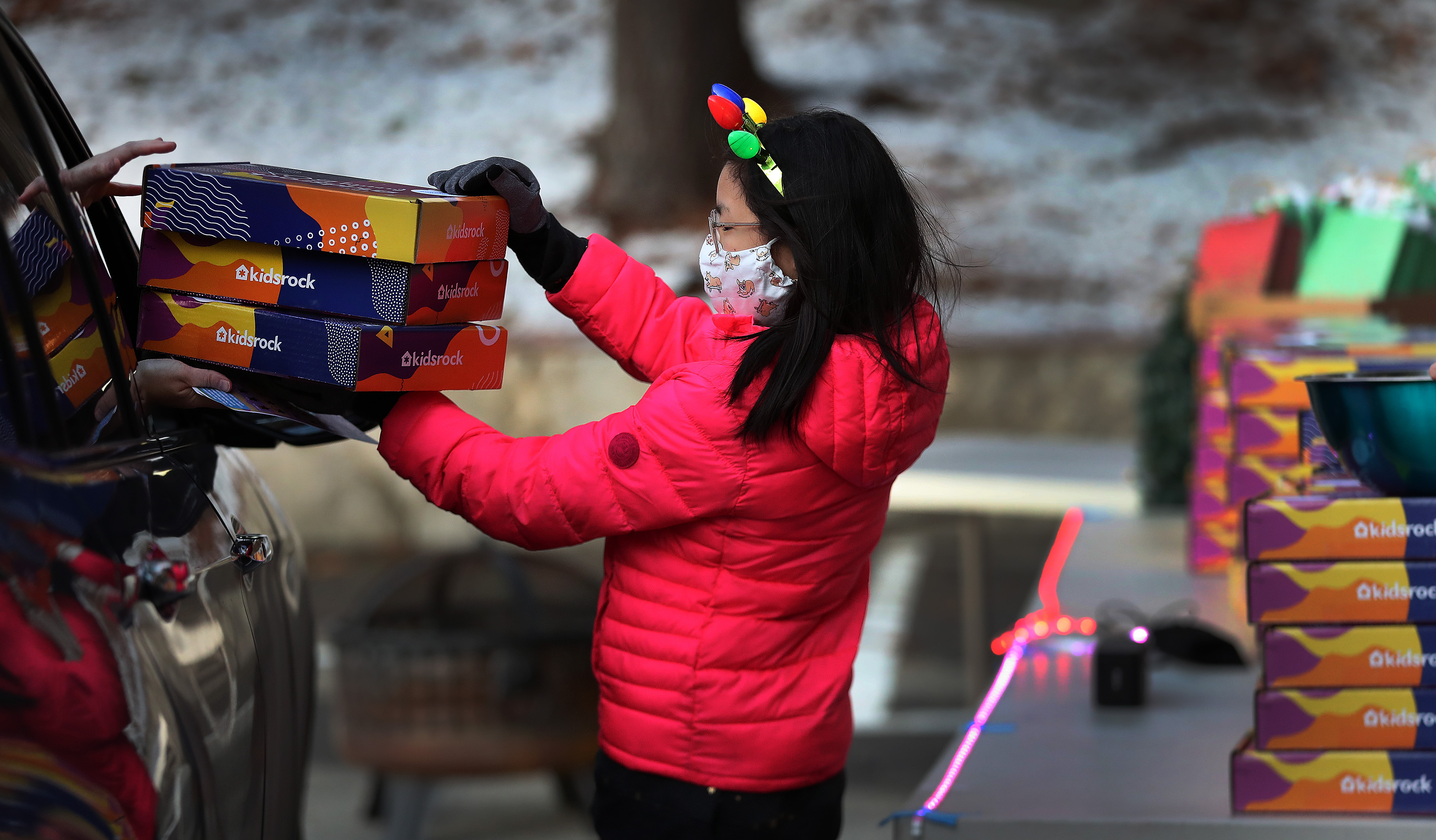 At a drive-through Christmas party for families of Highrock Acton, 11-year-old Noa Myung, the daughter of the organizer Phyllis Myung, handed out gift boxes.